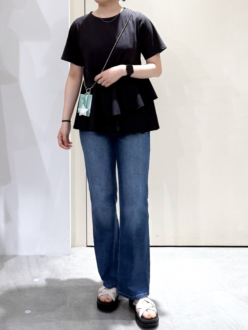 ブラック系のTシャツ/カットソー、ブルー系のデニムパンツ、ホワイト系のサンダルを着用したレディースの夏コーディネートの2枚目の写真
