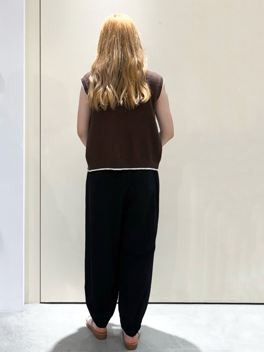 ブラウン系のベスト、ブラック系のその他パンツ、ホワイト系のショルダーバッグを着用したレディースの夏コーディネートの3枚目の写真