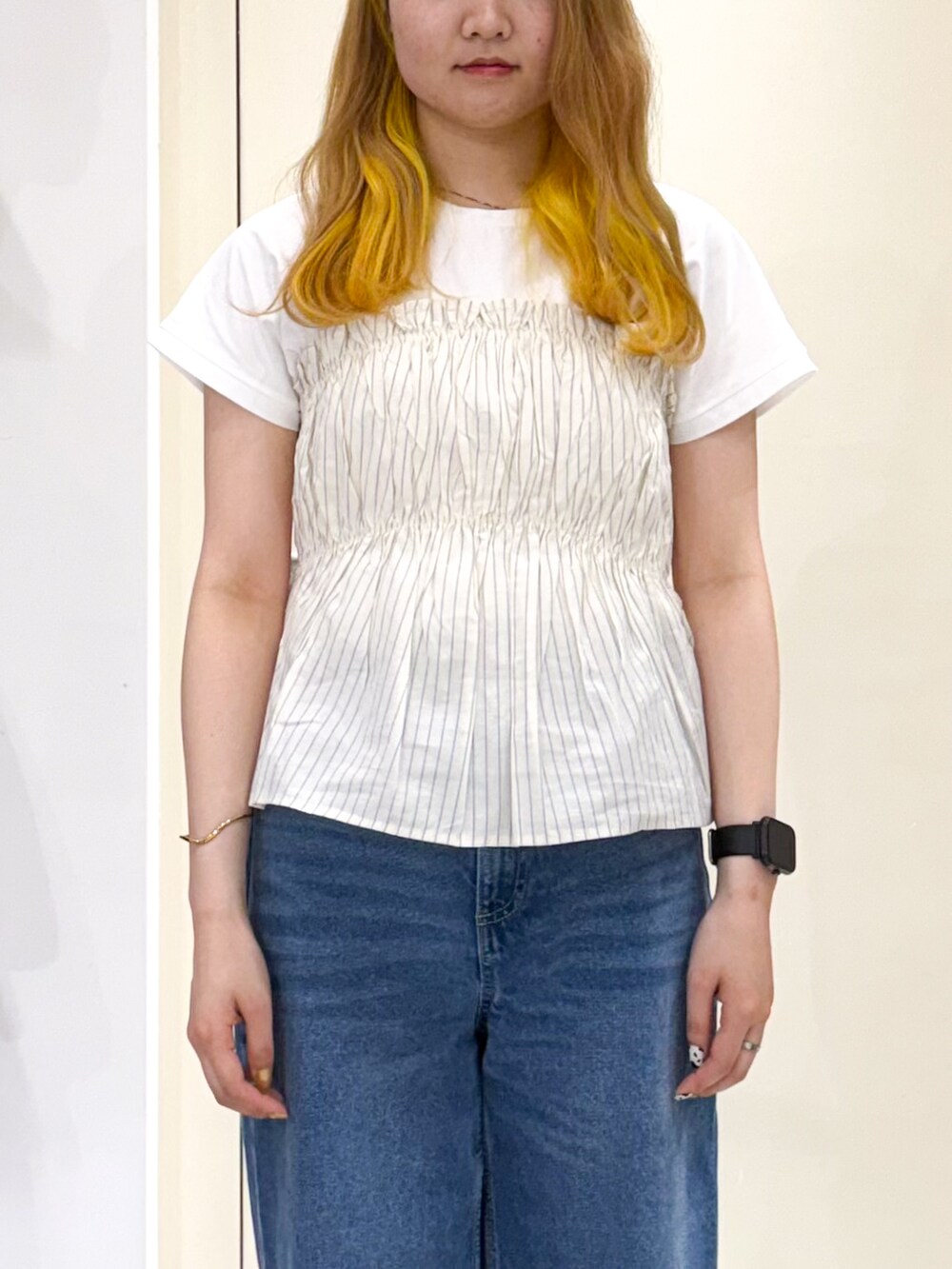 ブルー系のデニムパンツ、シルバー系のトートバッグ、ベージュ系のTシャツ/カットソーを着用したレディースの春コーディネートの4枚目の写真