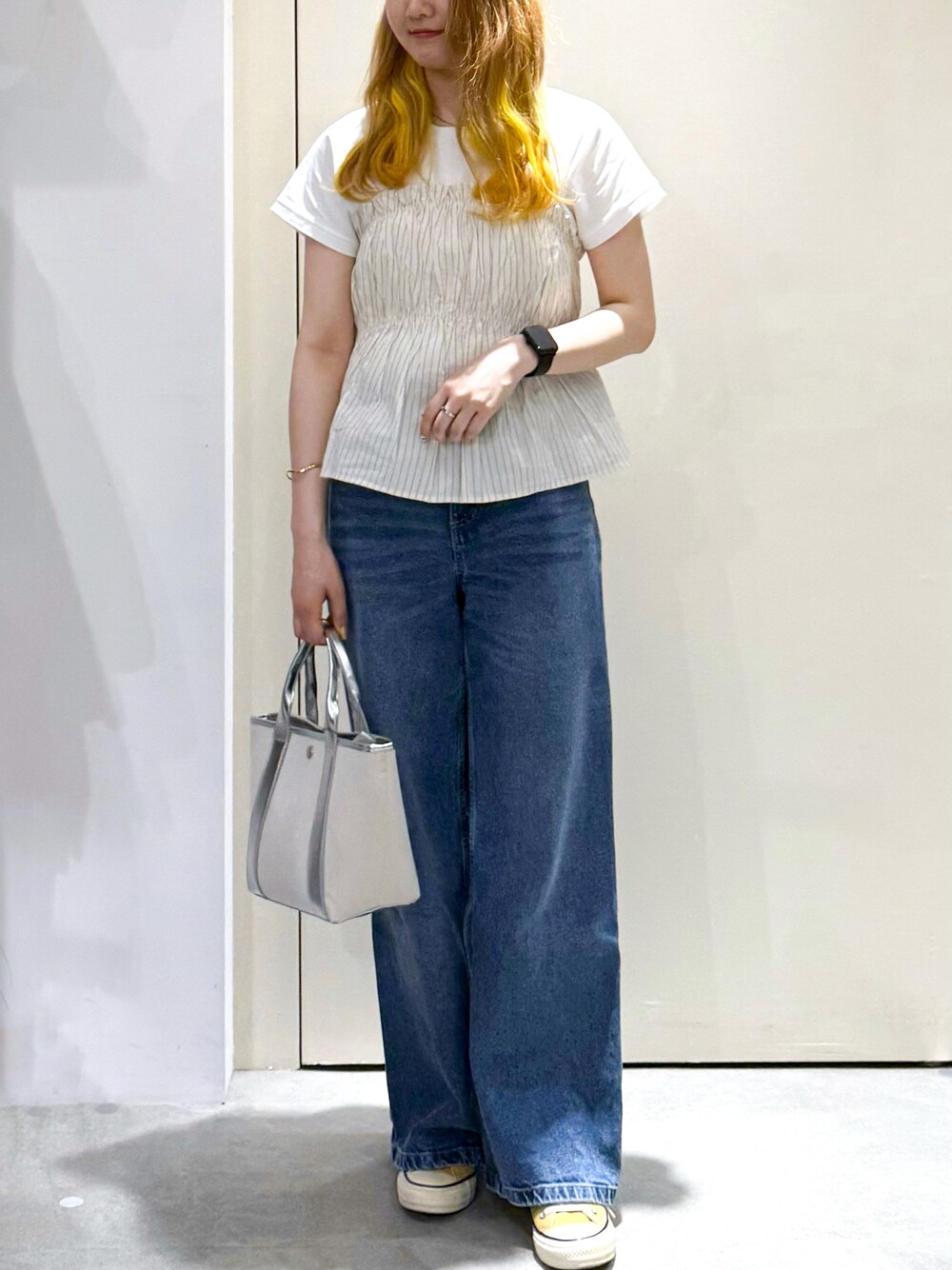 ブルー系のデニムパンツ、シルバー系のトートバッグ、ベージュ系のTシャツ/カットソーを着用したレディースの春コーディネートの2枚目の写真