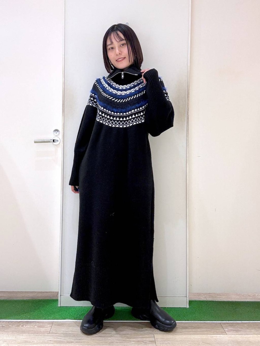 シルバー系のショルダーバッグ、ブラック系のブーツ、ブラック系のワンピースを着用したレディースの秋コーディネートの2枚目の写真