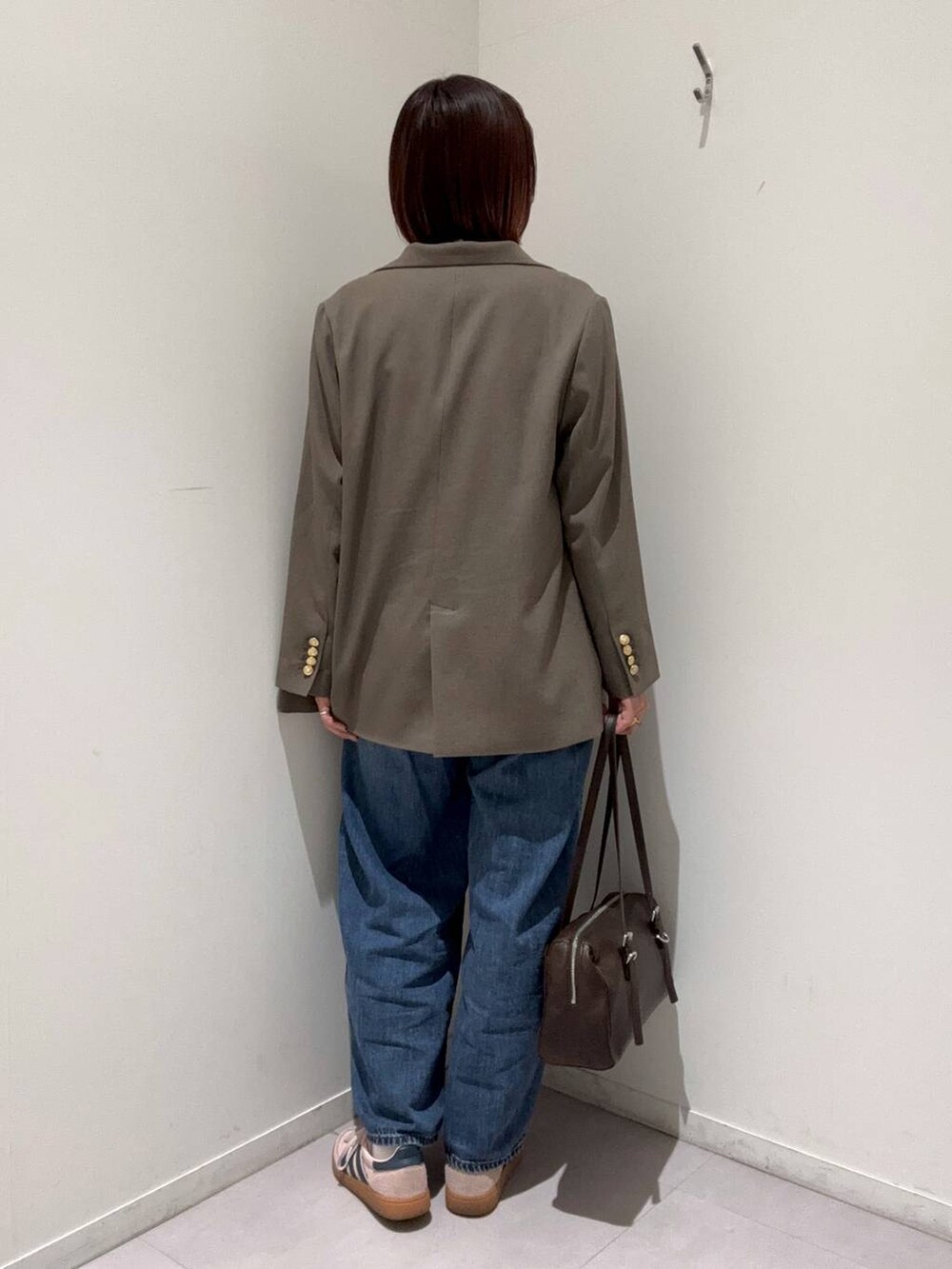 ブルー系のデニムパンツ、ブラウン系のテーラードジャケット、ブラウン系のショルダーバッグを着用したレディースの春コーディネートの3枚目の写真