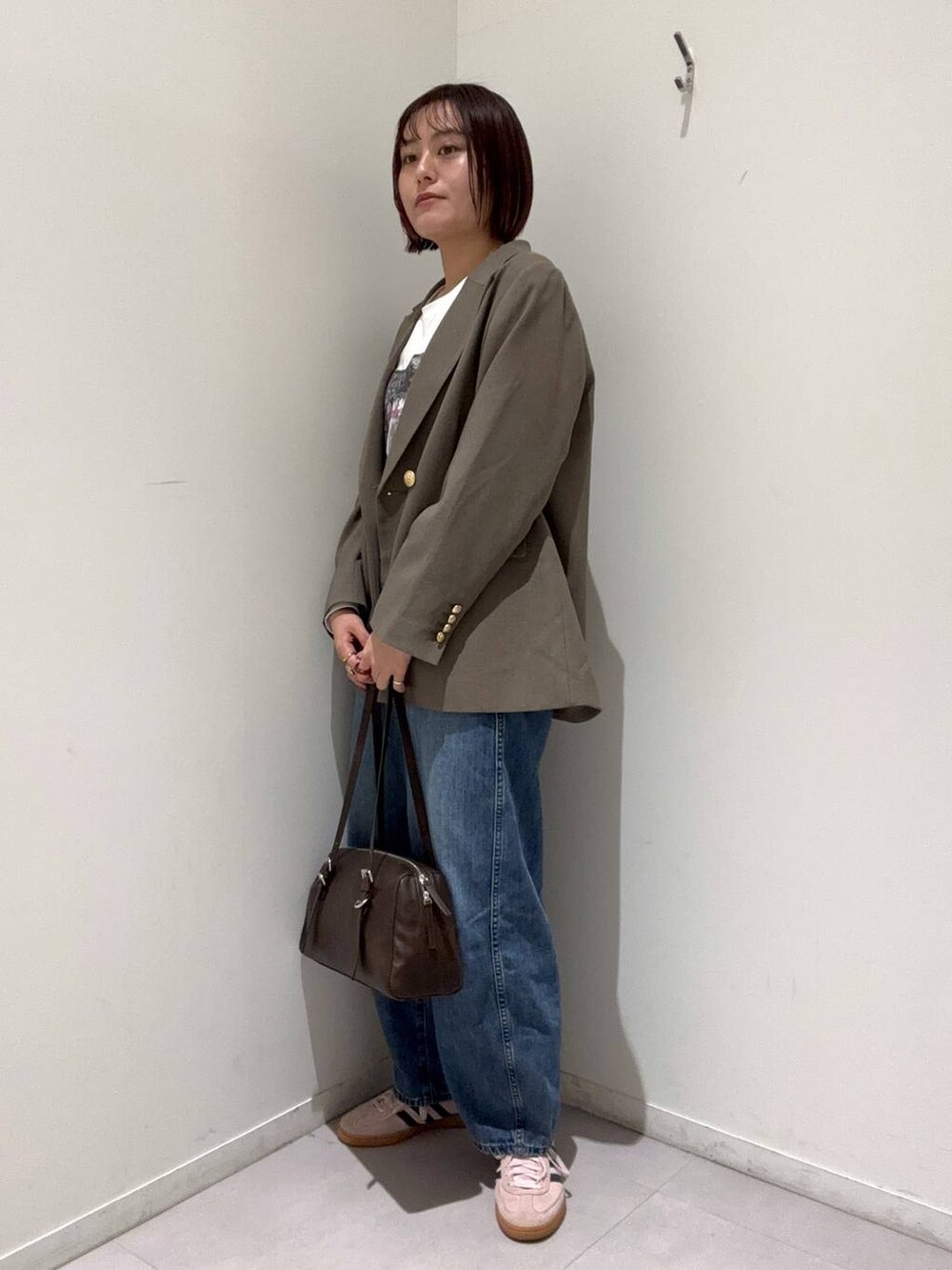 ブルー系のデニムパンツ、ブラウン系のテーラードジャケット、ブラウン系のショルダーバッグを着用したレディースの春コーディネートの2枚目の写真