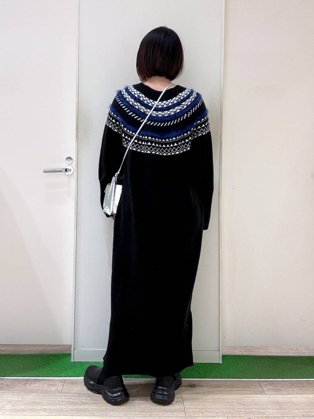 シルバー系のショルダーバッグ、ブラック系のブーツ、ブラック系のワンピースを着用したレディースの秋コーディネートの4枚目の写真