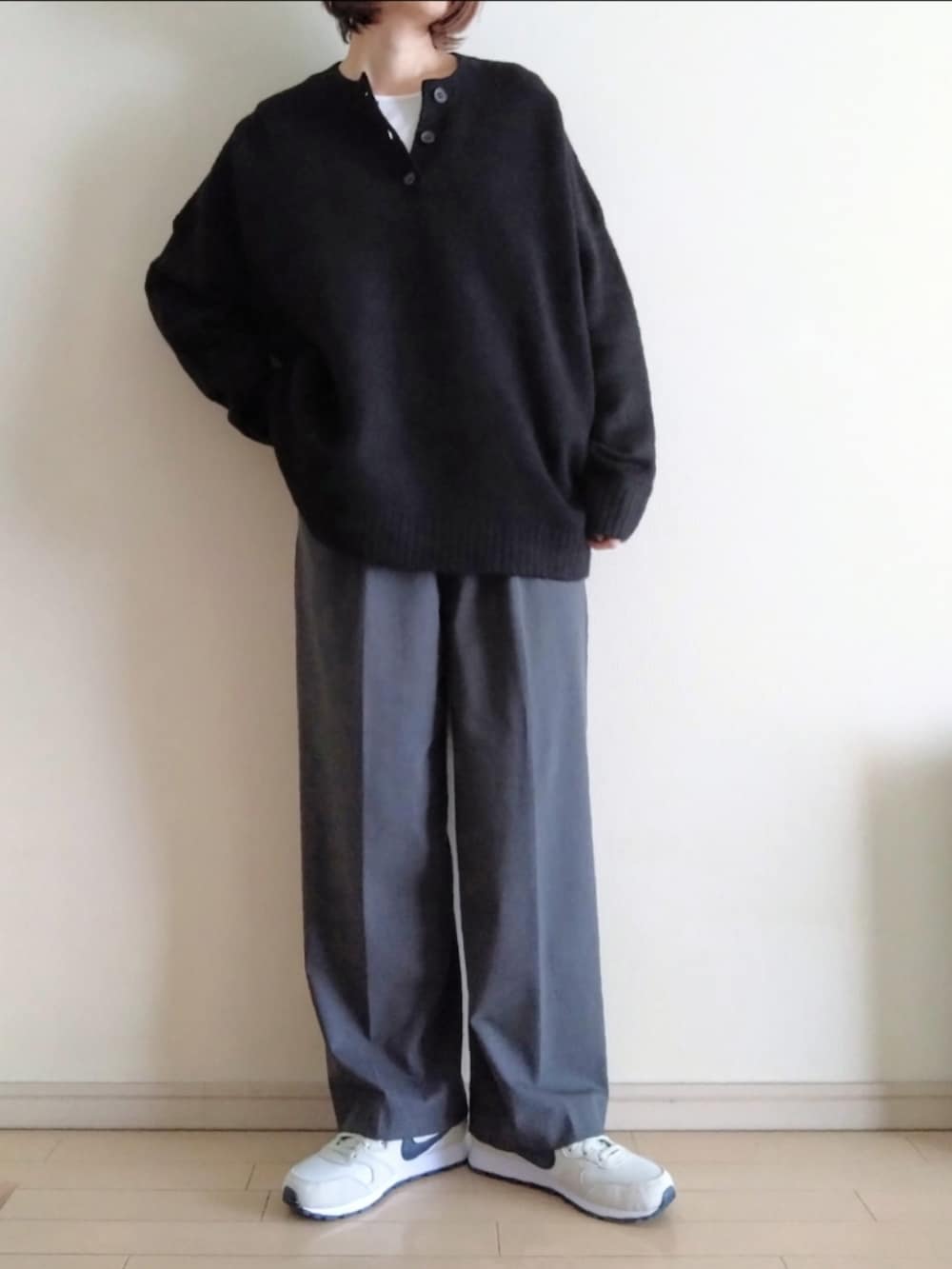 ブラック系のニット/セーター、ホワイト系のTシャツ/カットソー、グレー系のスラックスを着用したレディースの秋コーディネートの2枚目の写真