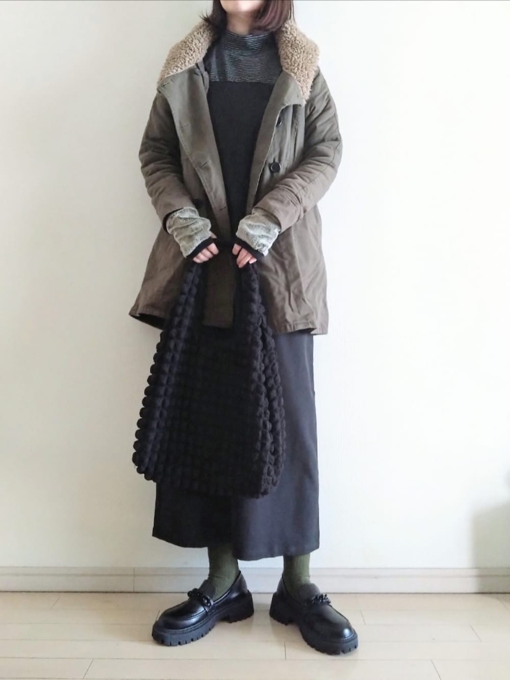 グリーン系のモッズコート、ブラック系のワンピース、ブラック系のTシャツ/カットソーを着用したレディースの冬コーディネートの2枚目の写真