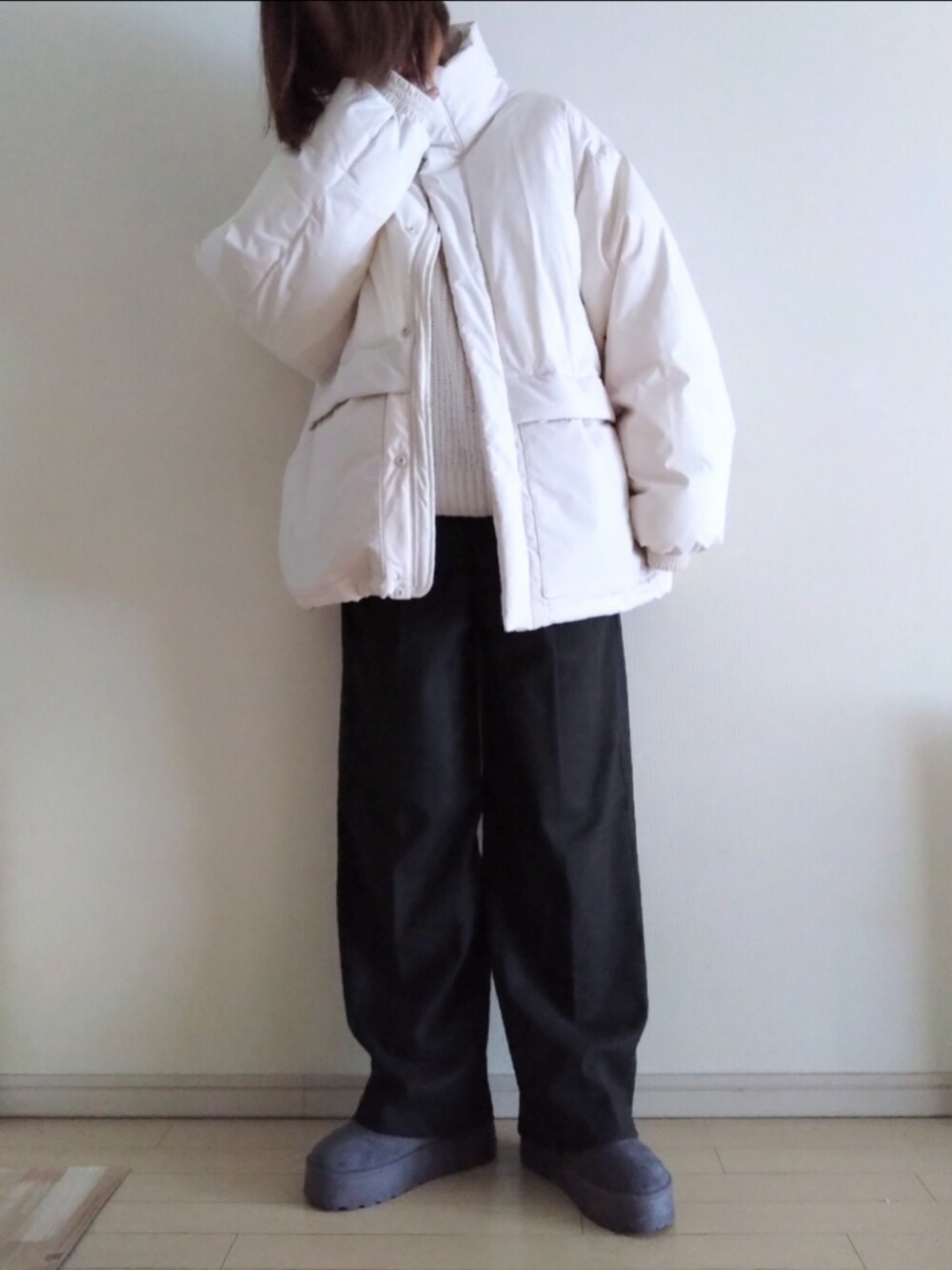 ホワイト系のダウンジャケット/コート、ホワイト系のニット/セーター、グレー系のスラックスを着用したレディースの冬コーディネートの2枚目の写真