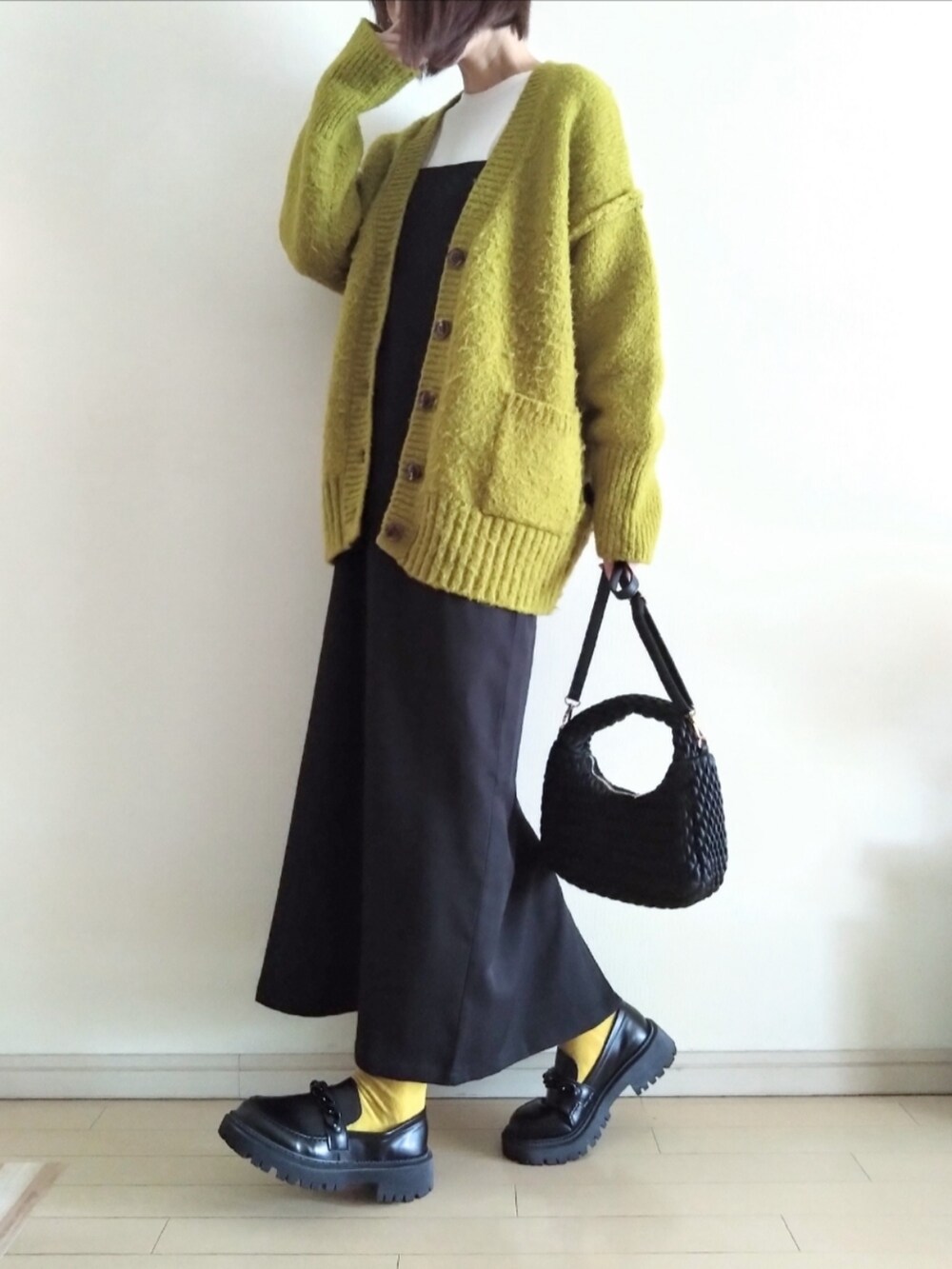 グリーン系のカーディガン/ボレロ、ホワイト系のTシャツ/カットソー、ブラック系のワンピースを着用したレディースの春コーディネートの2枚目の写真