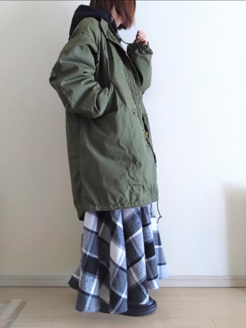 グリーン系のモッズコート、ブラック系のパーカー、ブラック系のスカートを着用したレディースの冬コーディネートの2枚目の写真