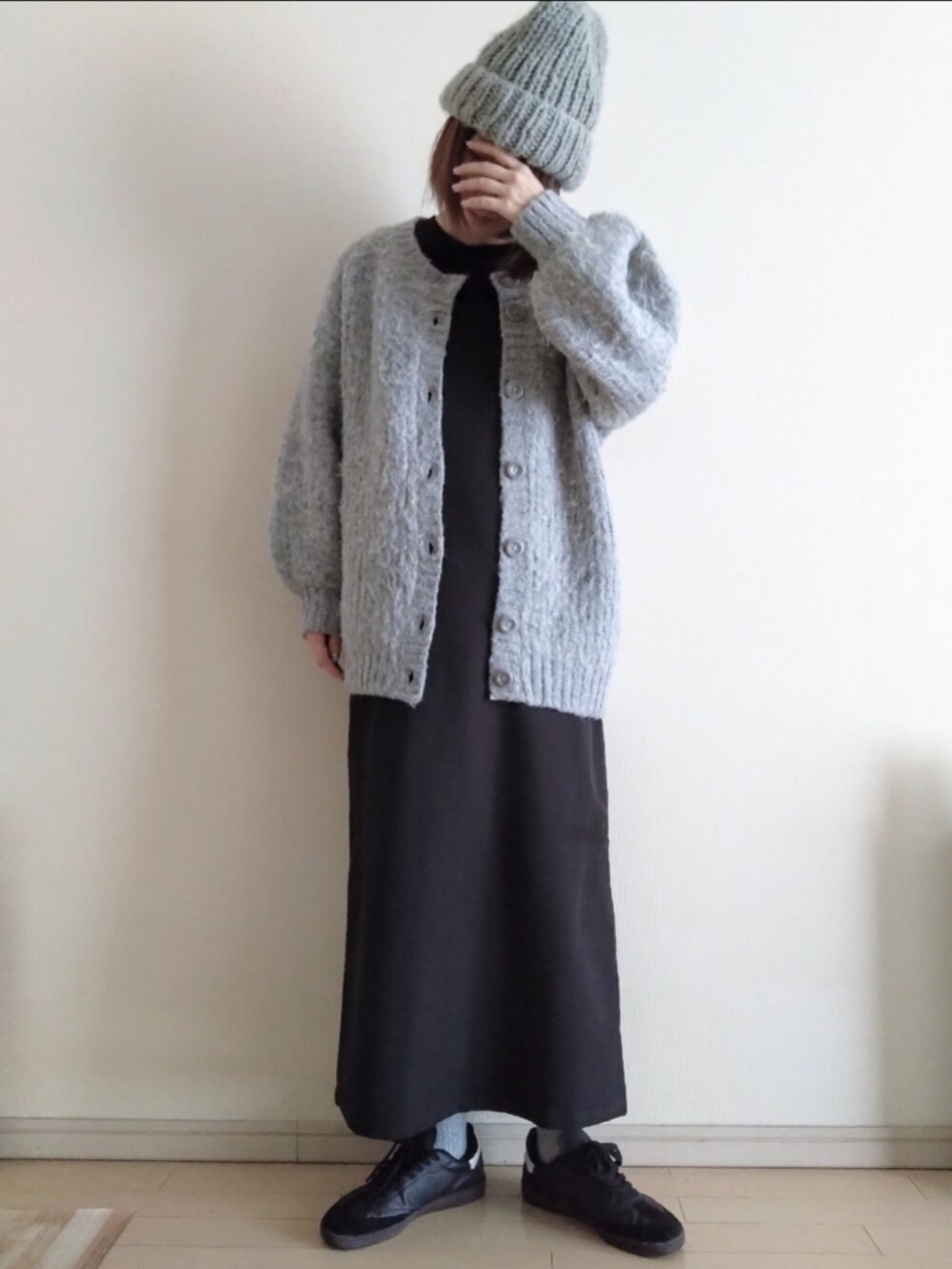 グレー系のカーディガン/ボレロ、ブラック系のワンピース、ブラック系のスニーカーを着用したレディースの冬コーディネートの2枚目の写真