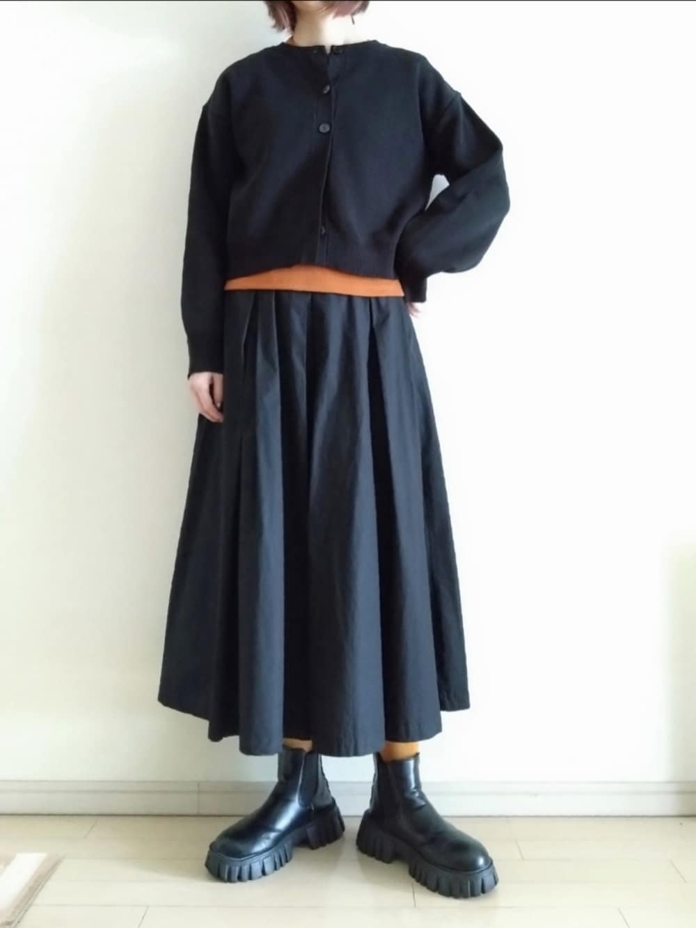 ブラック系のチェスターコート、ブラック系のカーディガン/ボレロ、ブラウン系のTシャツ/カットソーを着用したレディースの冬コーディネートの2枚目の写真