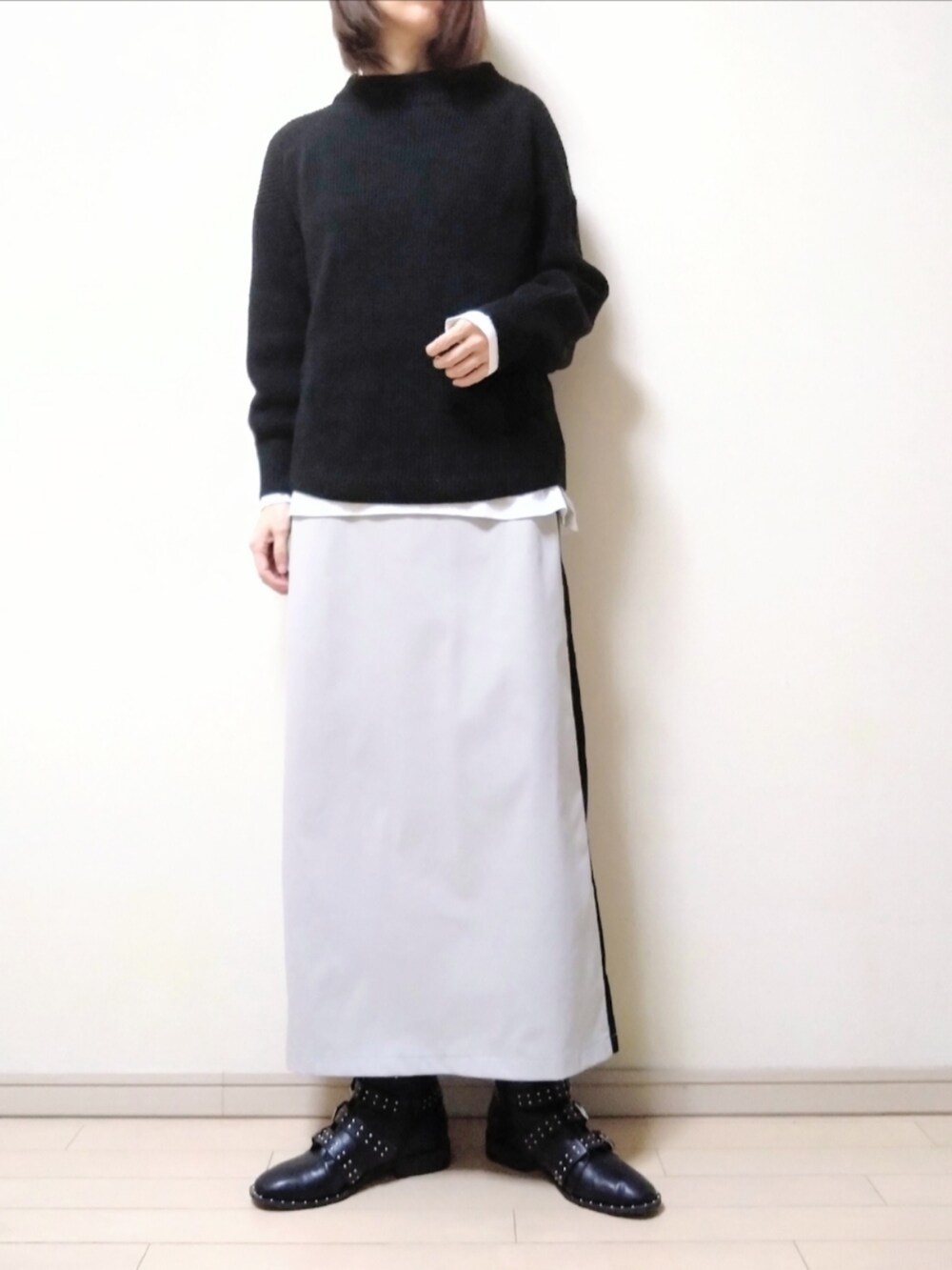 ブラック系のニット/セーター、ホワイト系のTシャツ/カットソー、ベージュ系のスカートを着用したレディースの秋コーディネートの2枚目の写真