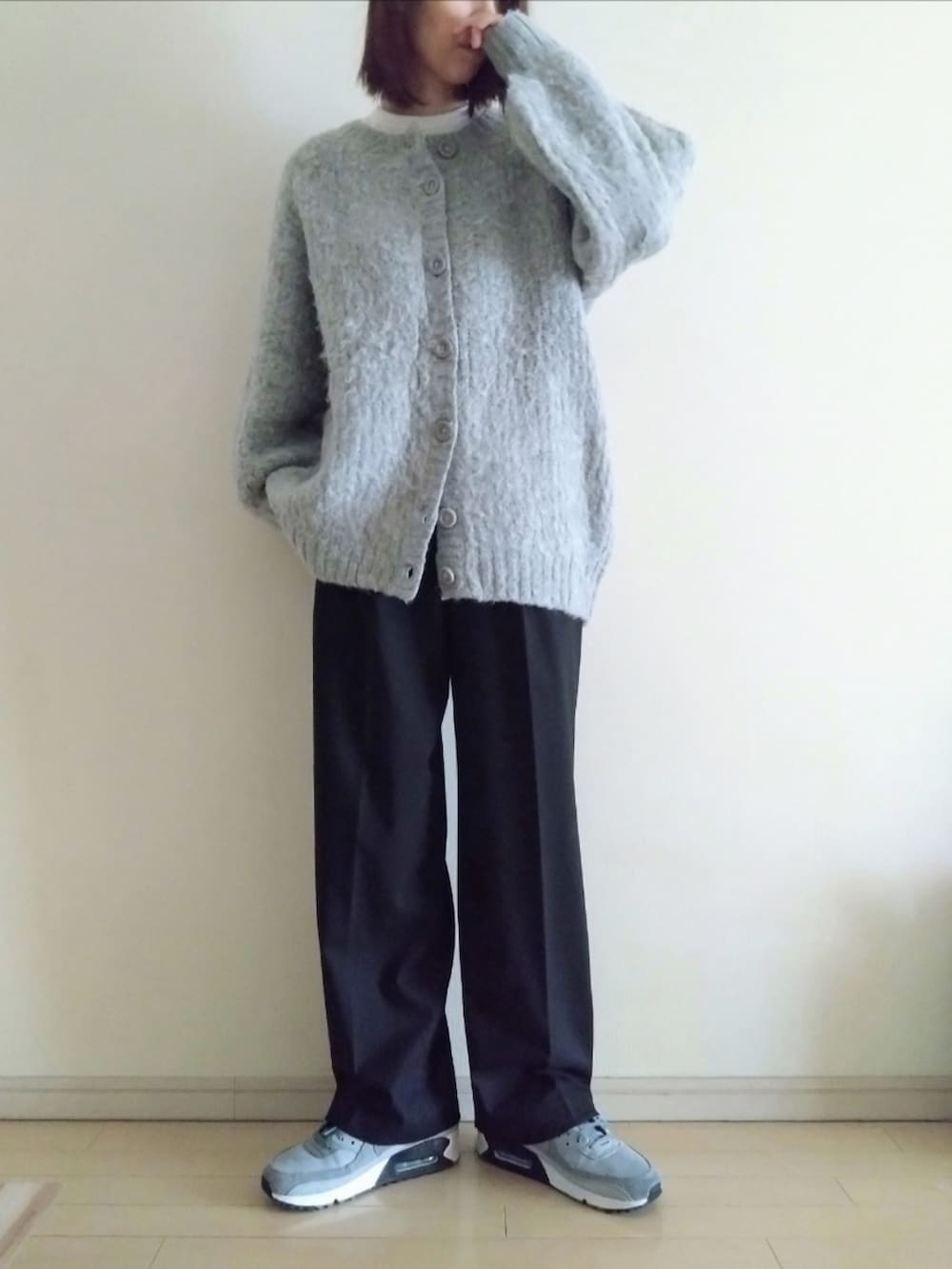 グレー系のカーディガン/ボレロ、ホワイト系のTシャツ/カットソー、ブラック系のスラックスを着用したレディースの冬コーディネートの2枚目の写真