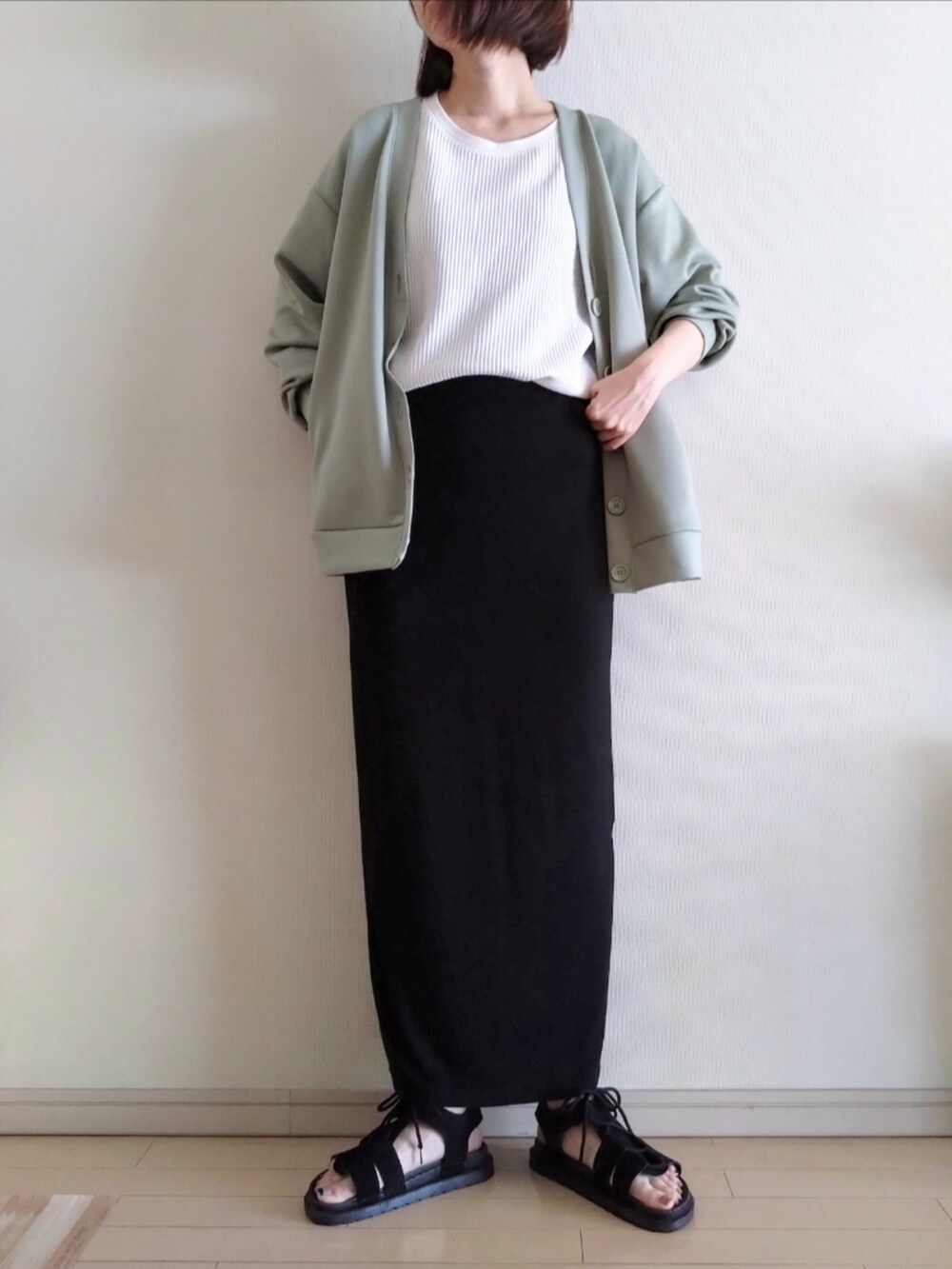 ホワイト系のTシャツ/カットソー、グリーン系のカーディガン/ボレロ、ブラック系のスカートを着用したレディースの春コーディネートの2枚目の写真
