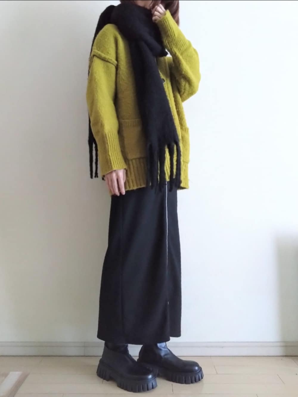 グリーン系のモッズコート、グリーン系のカーディガン/ボレロ、ブラック系のスカートを着用したレディースの冬コーディネートの2枚目の写真