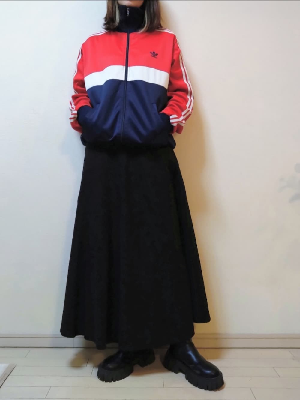 グリーン系のモッズコート、レッド系のジャージ、ブラック系のスカートを着用したレディースの冬コーディネートの2枚目の写真