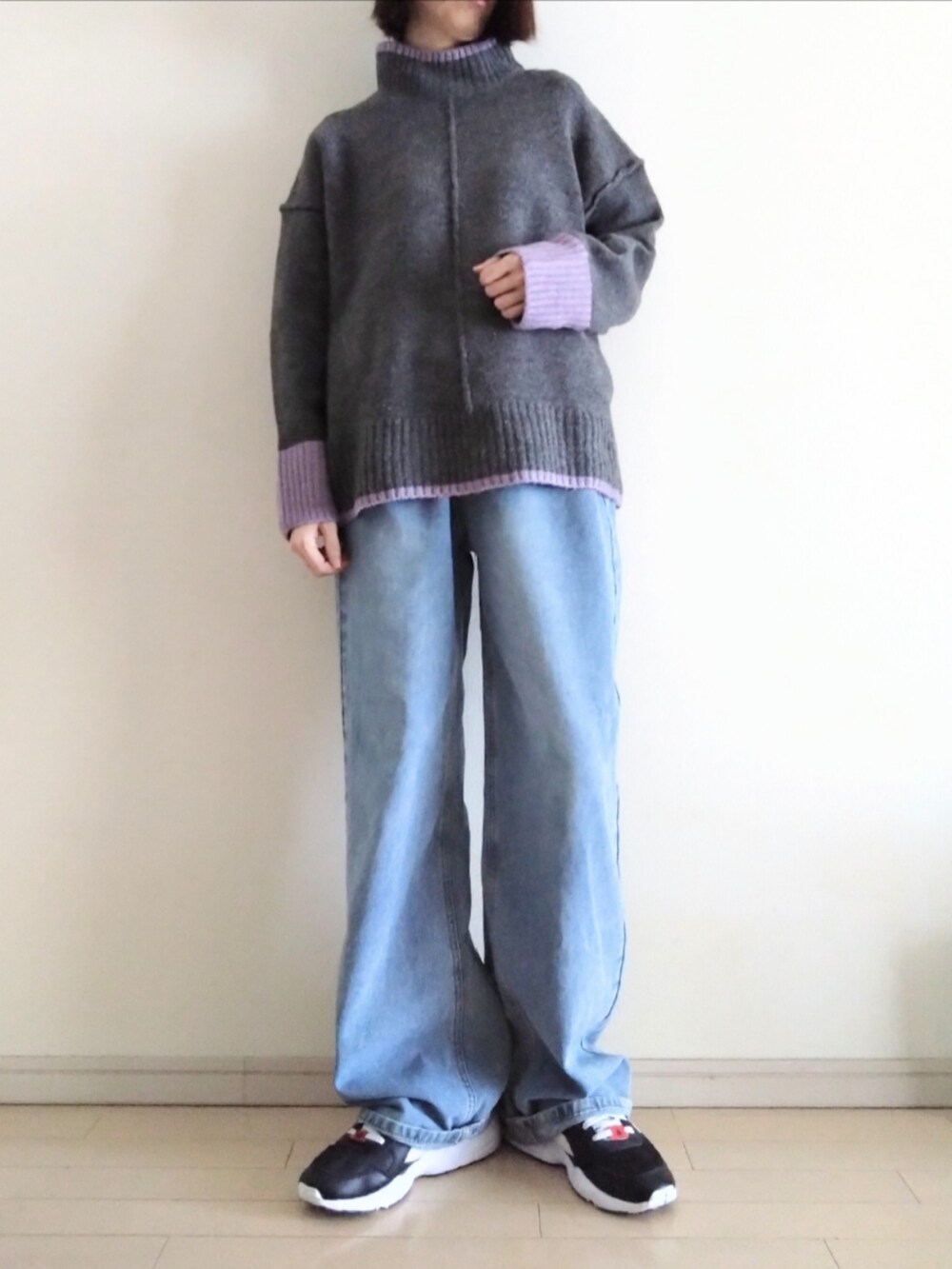 グレー系のニット/セーター、ブルー系のデニムパンツ、ブラック系のスニーカーを着用したレディースの秋コーディネートの2枚目の写真