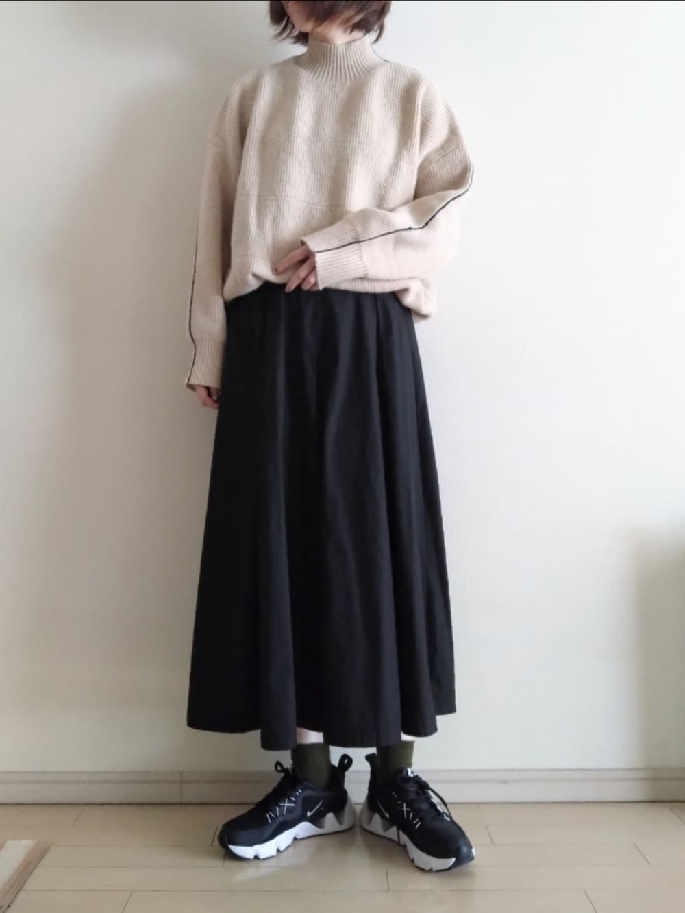 グリーン系のモッズコート、ベージュ系のニット/セーター、ブラック系のスカートを着用したレディースの冬コーディネートの2枚目の写真