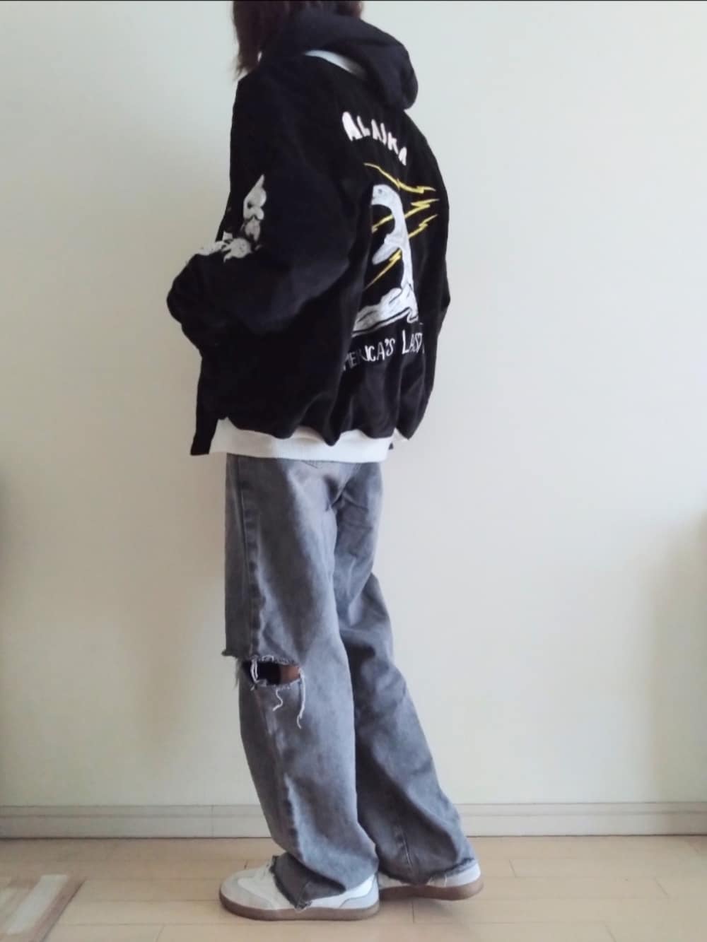 ブラック系のスカジャン、ブラック系のパーカー、グレー系のデニムパンツを着用したレディースの春コーディネートの2枚目の写真