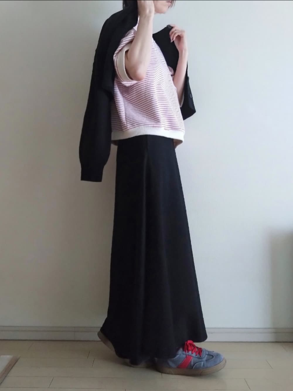 レッド系のスウェット、ブラック系のカーディガン/ボレロ、ブラック系のスカートを着用したレディースの春コーディネートの2枚目の写真