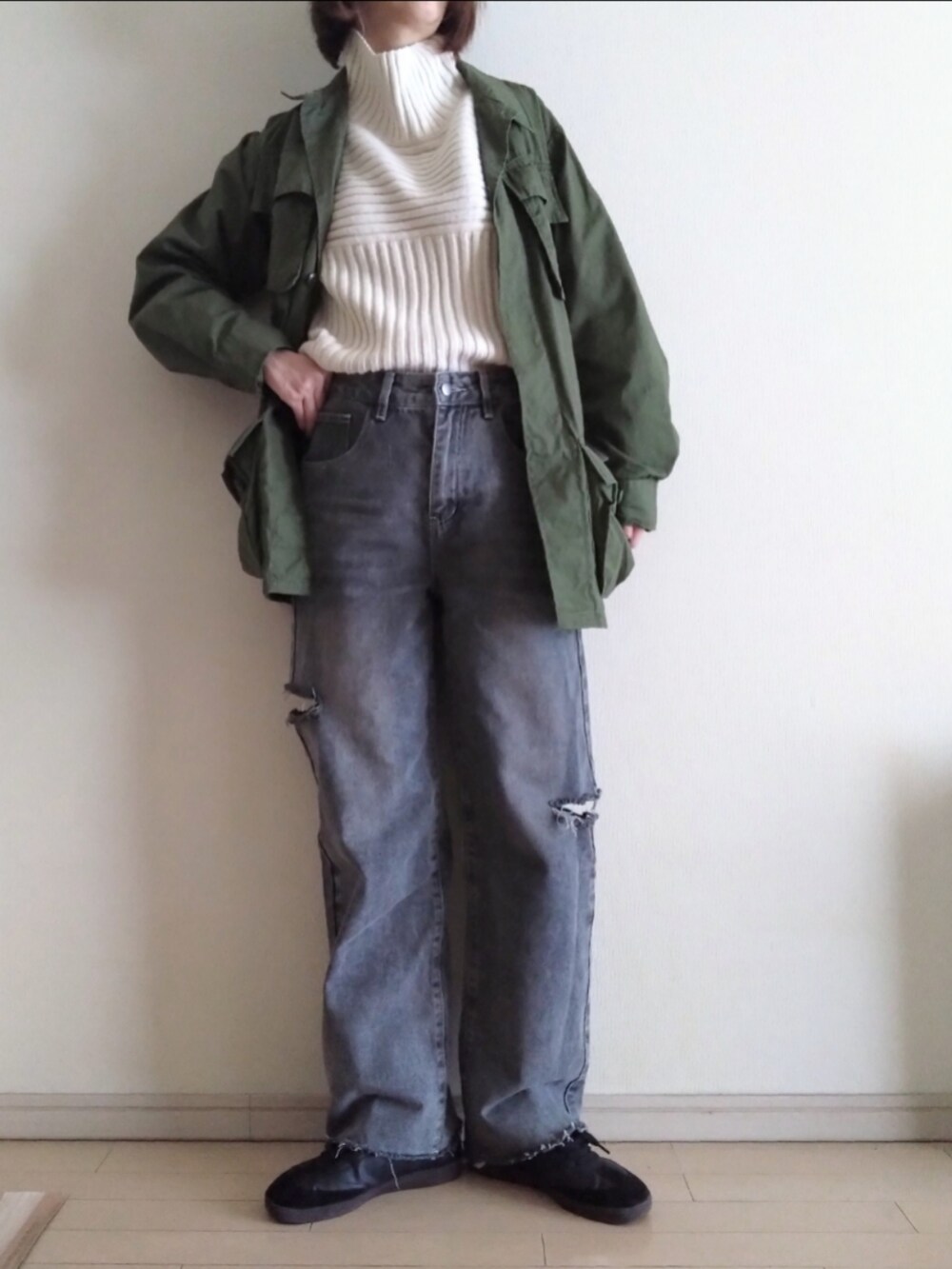 グリーン系のミリタリージャケット、ホワイト系のニット/セーター、グレー系のデニムパンツを着用したレディースの冬コーディネートの2枚目の写真
