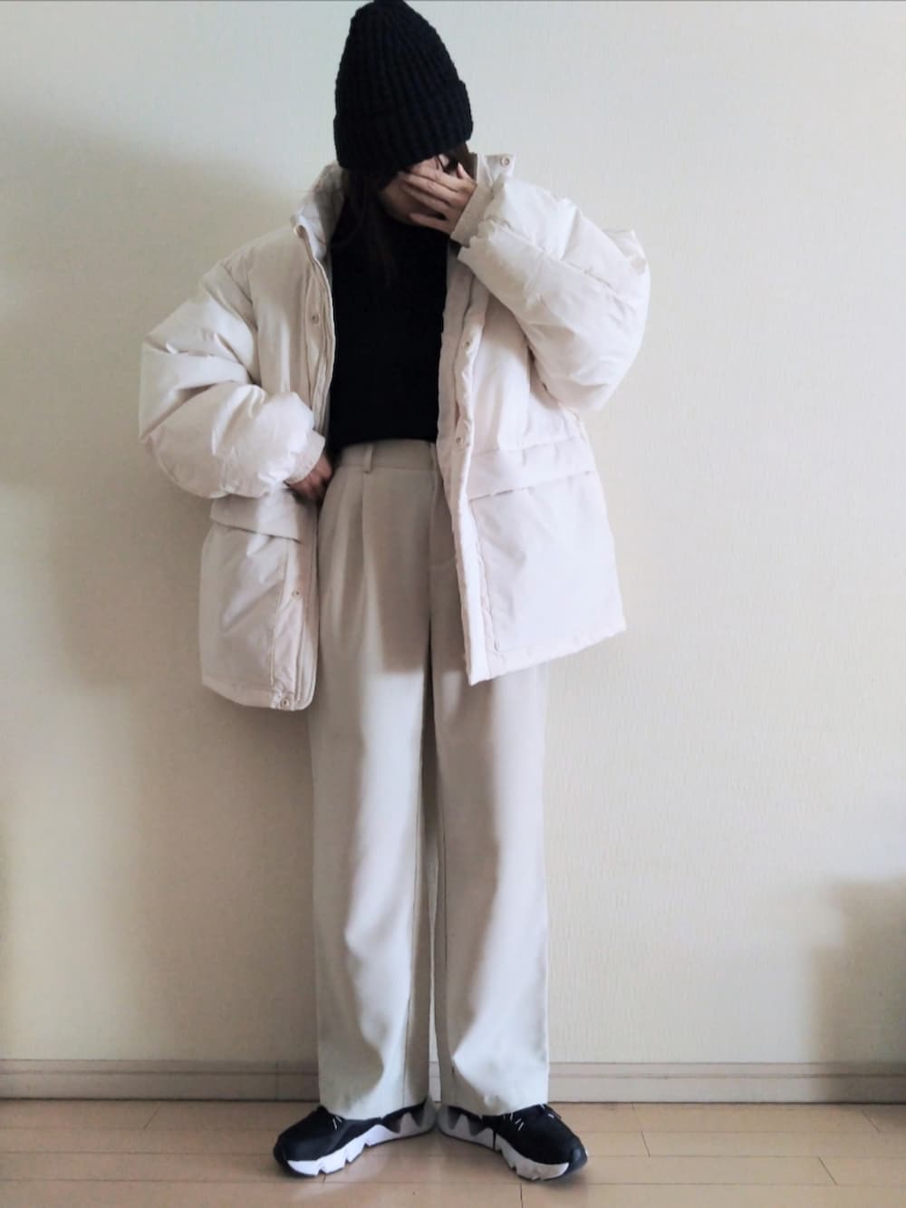 ホワイト系のダウンジャケット/コート、ブラック系のニット/セーター、ホワイト系のその他パンツを着用したレディースの冬コーディネートの2枚目の写真