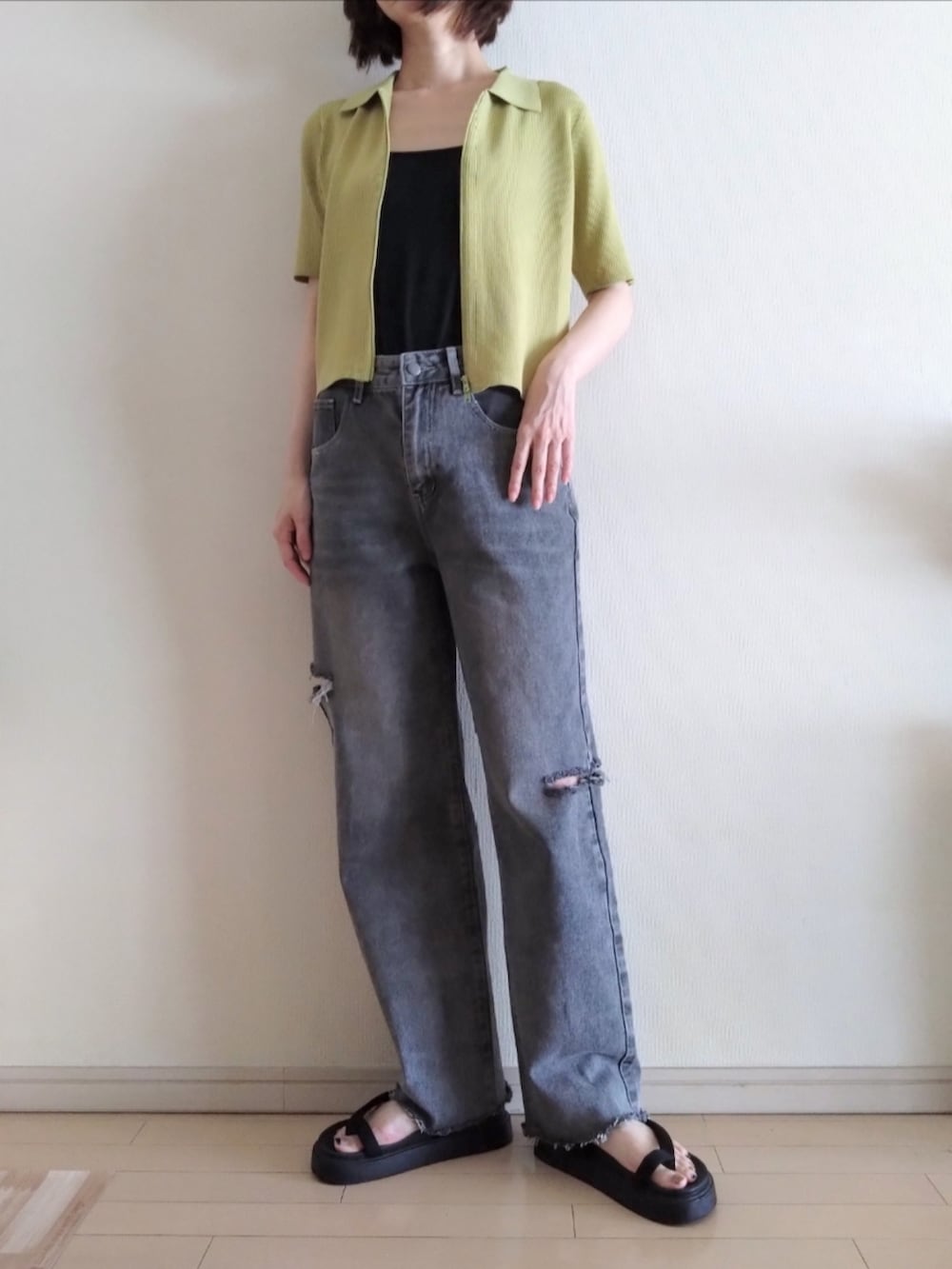 イエロー系のカーディガン/ボレロ、ブラック系のキャミソール、グレー系のデニムパンツを着用したレディースの春コーディネートの2枚目の写真