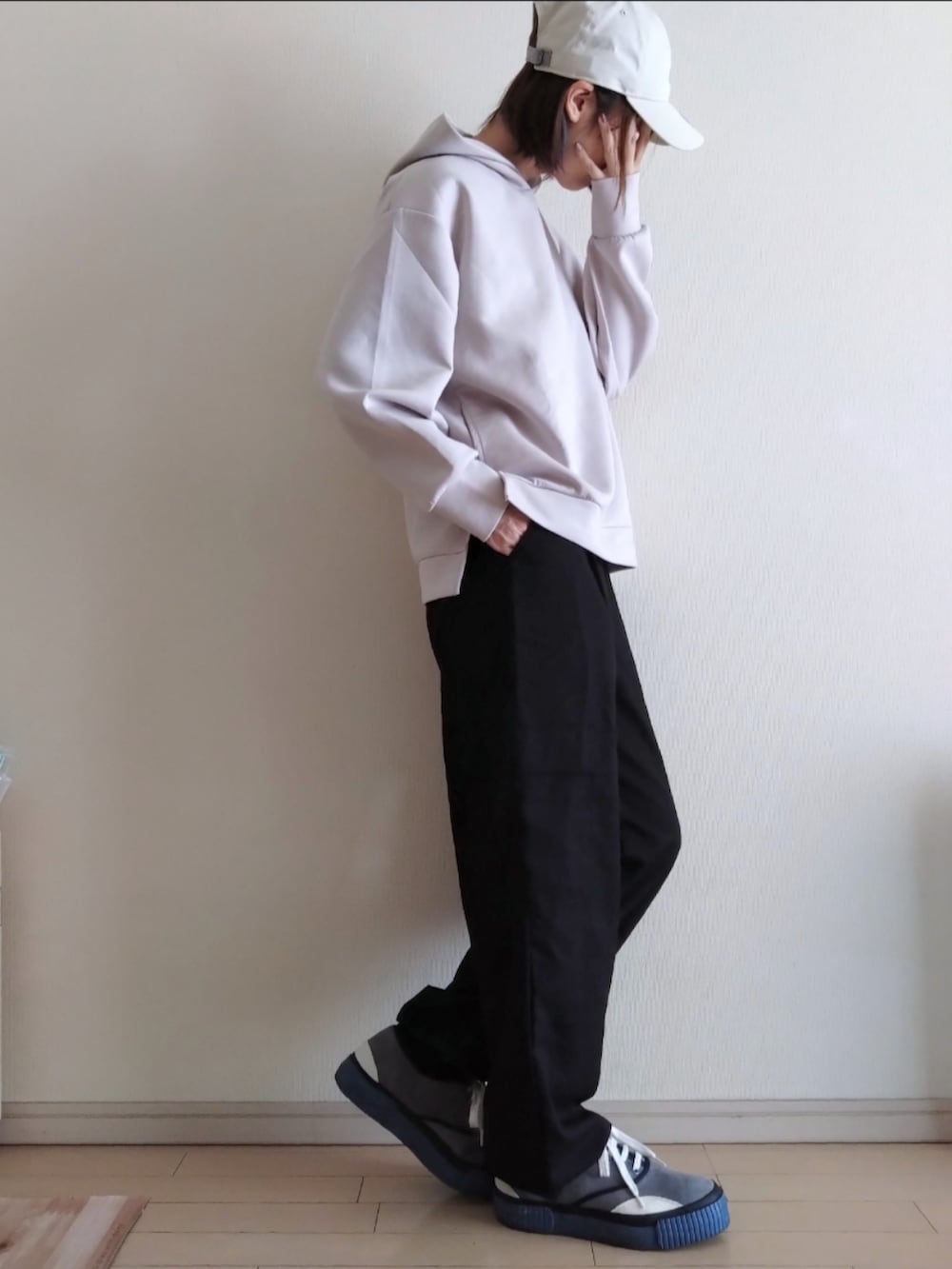 ベージュ系のパーカー、ブラック系のカーゴパンツ、ブルー系のスニーカーを着用したレディースの秋コーディネートの2枚目の写真
