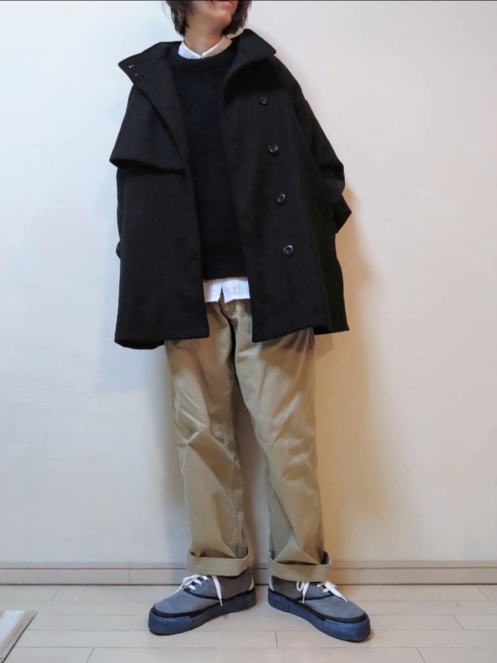 ブラック系のステンカラーコート、ブラック系のニット/セーター、グレー系のシャツ/ブラウスを着用したレディースの冬コーディネートの3枚目の写真