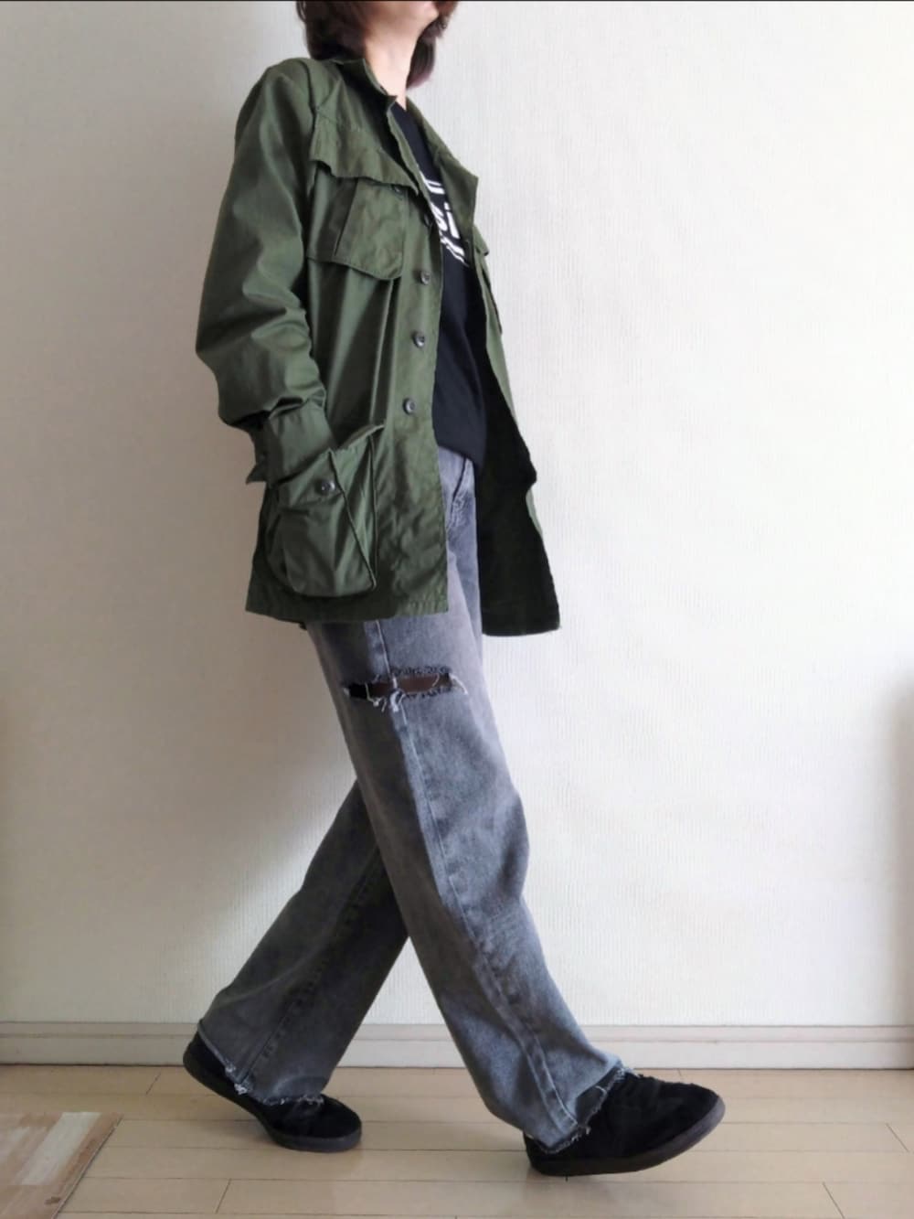 グリーン系のミリタリージャケット、ブラック系のTシャツ/カットソー、グレー系のデニムパンツを着用したレディースの秋コーディネートの2枚目の写真