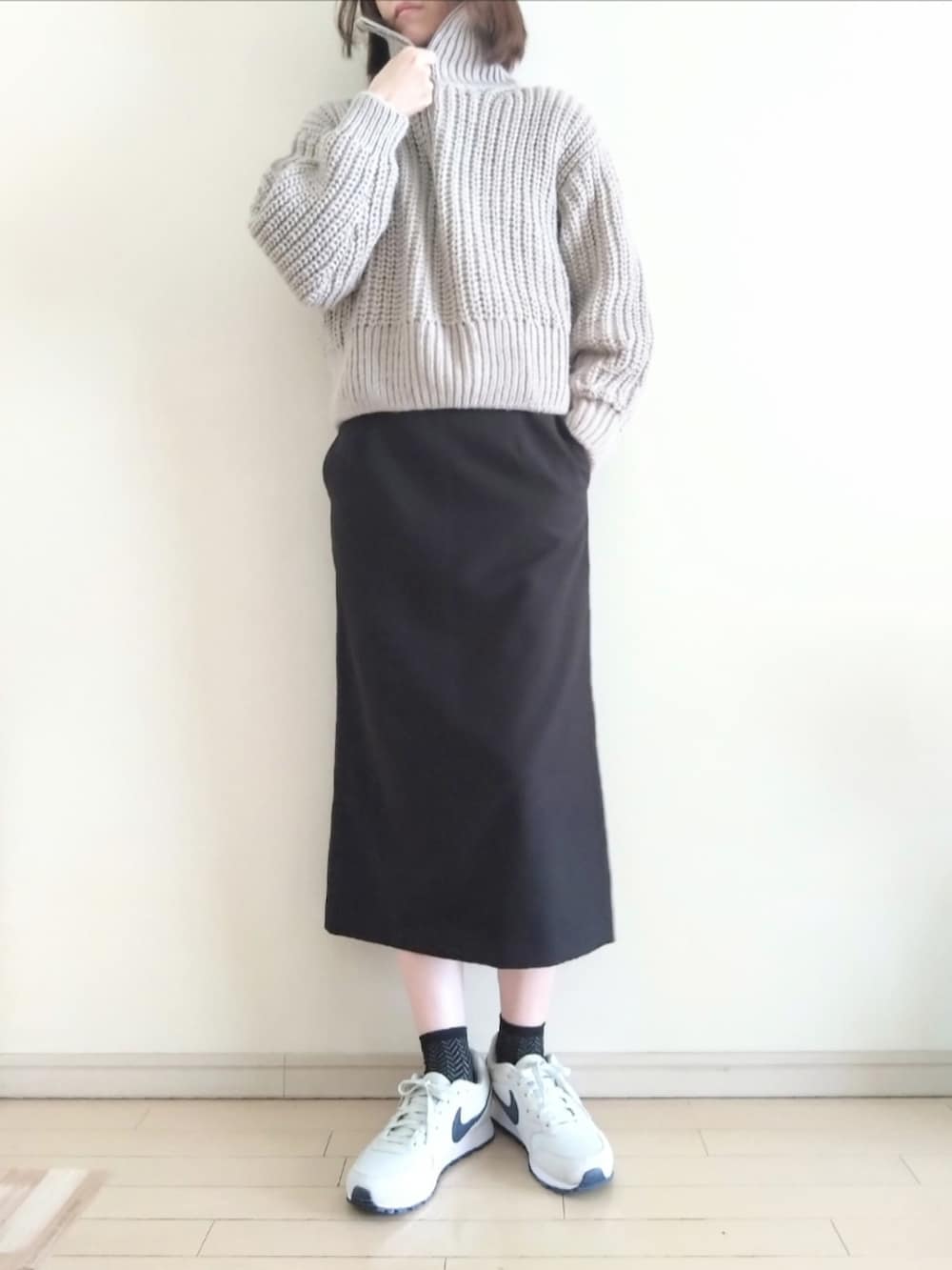 ベージュ系のニット/セーター、グレー系のTシャツ/カットソー、ブラック系のスカートを着用したレディースの春コーディネートの2枚目の写真