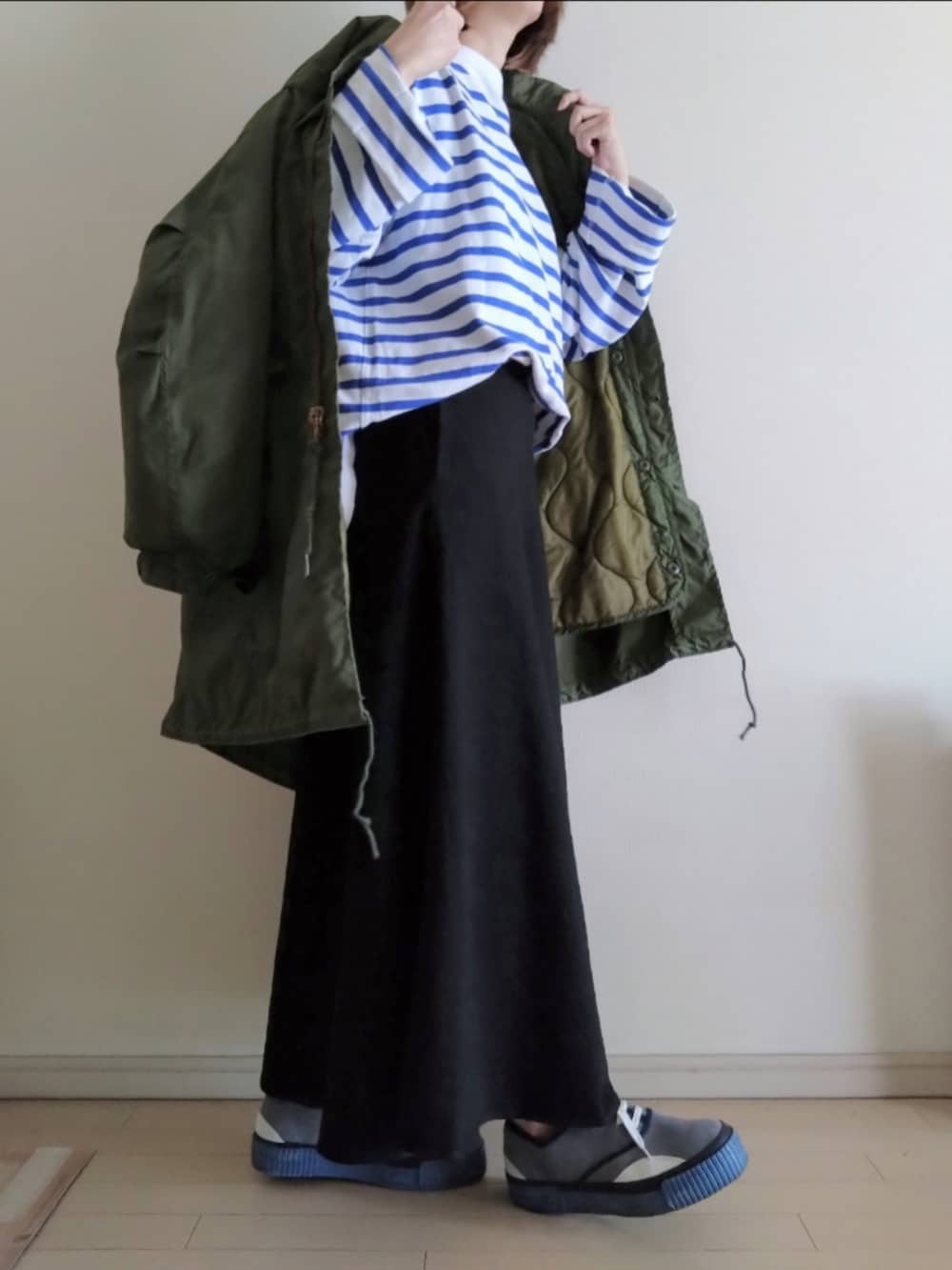 グリーン系のモッズコート、ブルー系のTシャツ/カットソー、ブラック系のスカートを着用したレディースの冬コーディネートの2枚目の写真