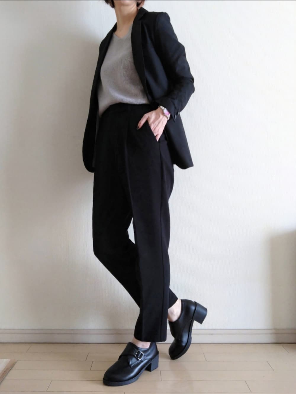 ブラック系のテーラードジャケット、グレー系のニット/セーター、ブラック系のスラックスを着用したレディースの春コーディネートの2枚目の写真