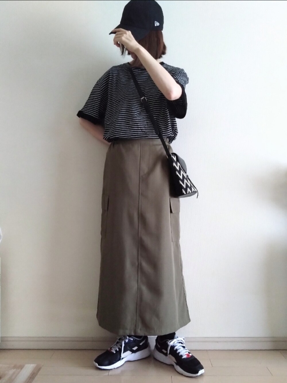ブラック系のTシャツ/カットソー、グリーン系のスカート、ブラック系のスニーカーを着用したレディースの夏コーディネートの2枚目の写真