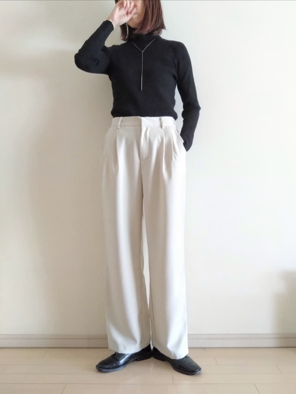 ブラック系のチェスターコート、ブラック系のニット/セーター、ホワイト系のその他パンツを着用したレディースの冬コーディネートの3枚目の写真