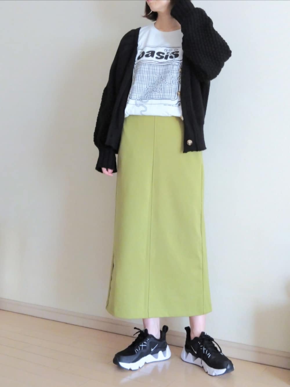 グリーン系のスカート、ブラック系のカーディガン/ボレロ、ホワイト系のTシャツ/カットソーを着用したレディースの秋コーディネートの2枚目の写真