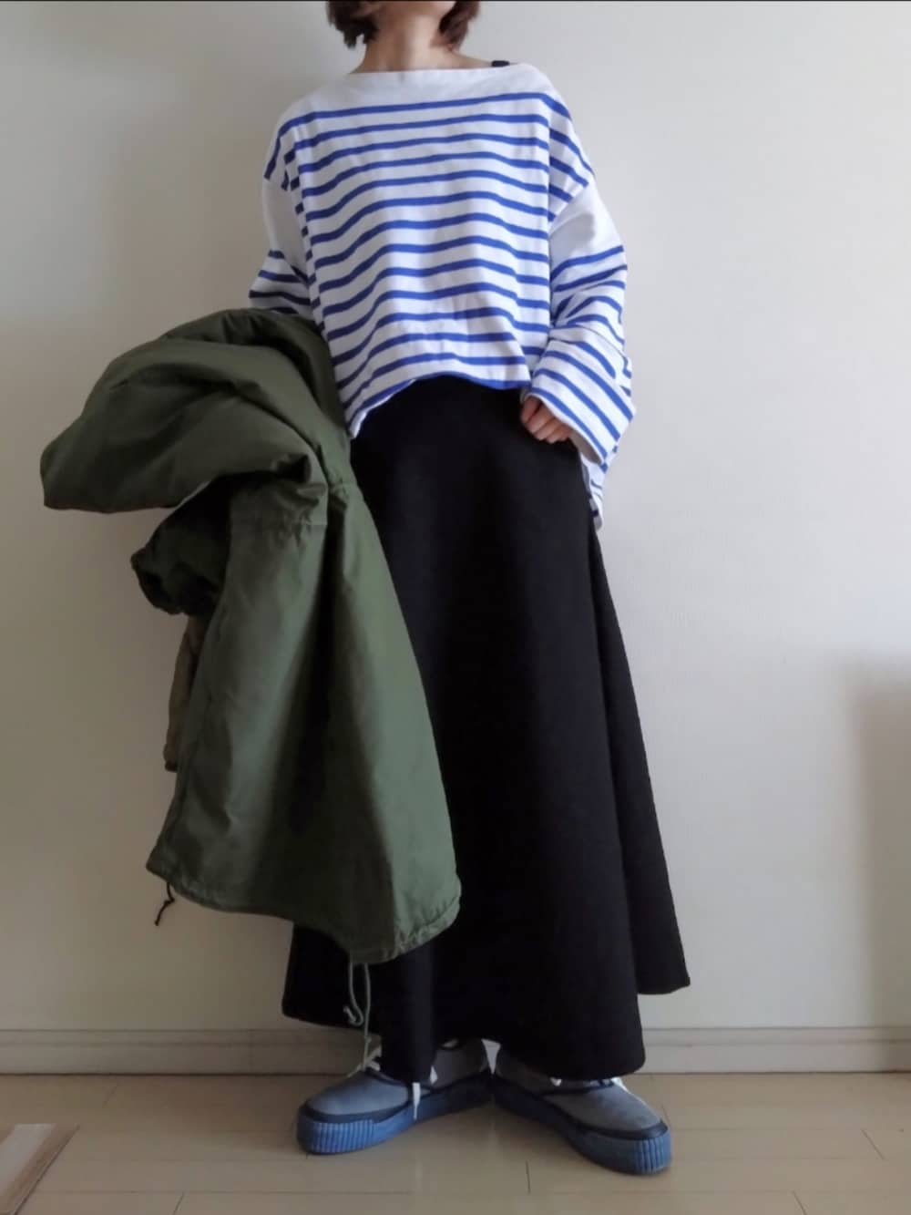 グリーン系のモッズコート、ブルー系のTシャツ/カットソー、ブラック系のスカートを着用したレディースの冬コーディネートの3枚目の写真