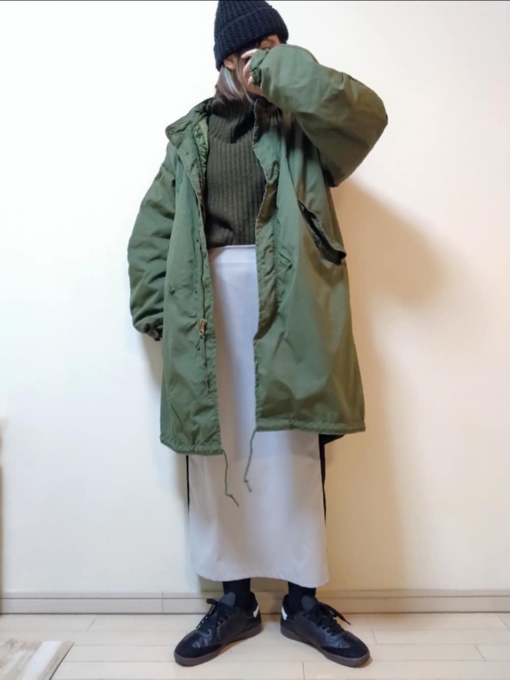 グリーン系のモッズコート、グリーン系のニット/セーター、ベージュ系のスカートを着用したレディースの冬コーディネートの2枚目の写真