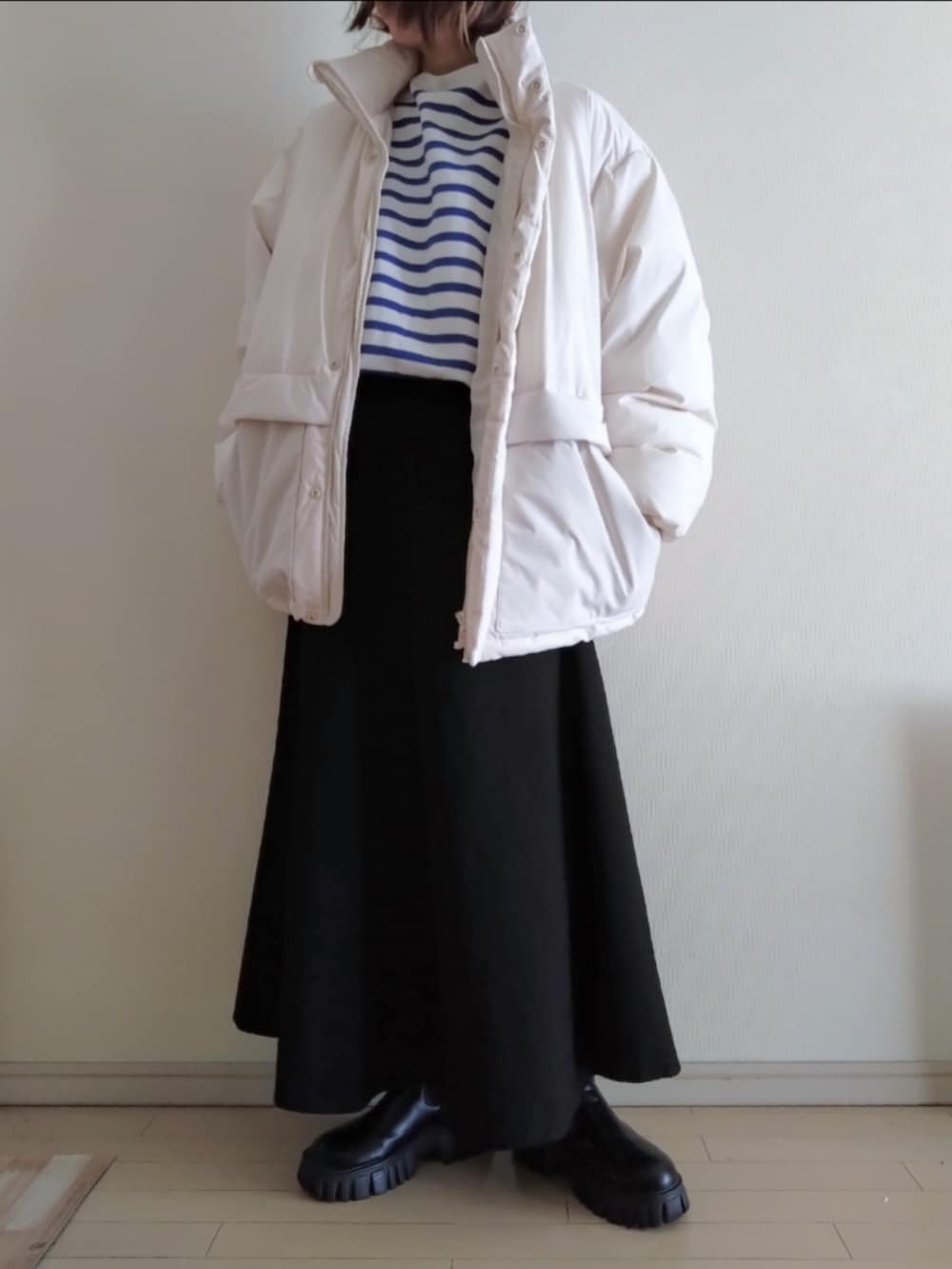 ブルー系のTシャツ/カットソー、ホワイト系のダウンジャケット/コート、ブラック系のスカートを着用したレディースの冬コーディネートの2枚目の写真