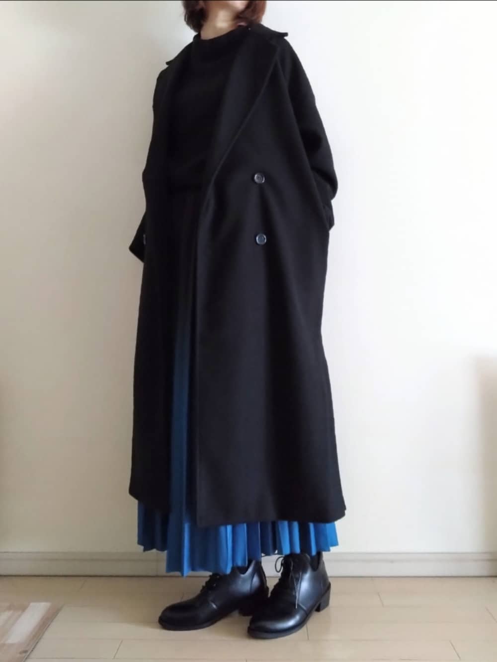 ブラック系のチェスターコート、ブラック系のニット/セーター、ブルー系のスカートを着用したレディースの冬コーディネートの2枚目の写真