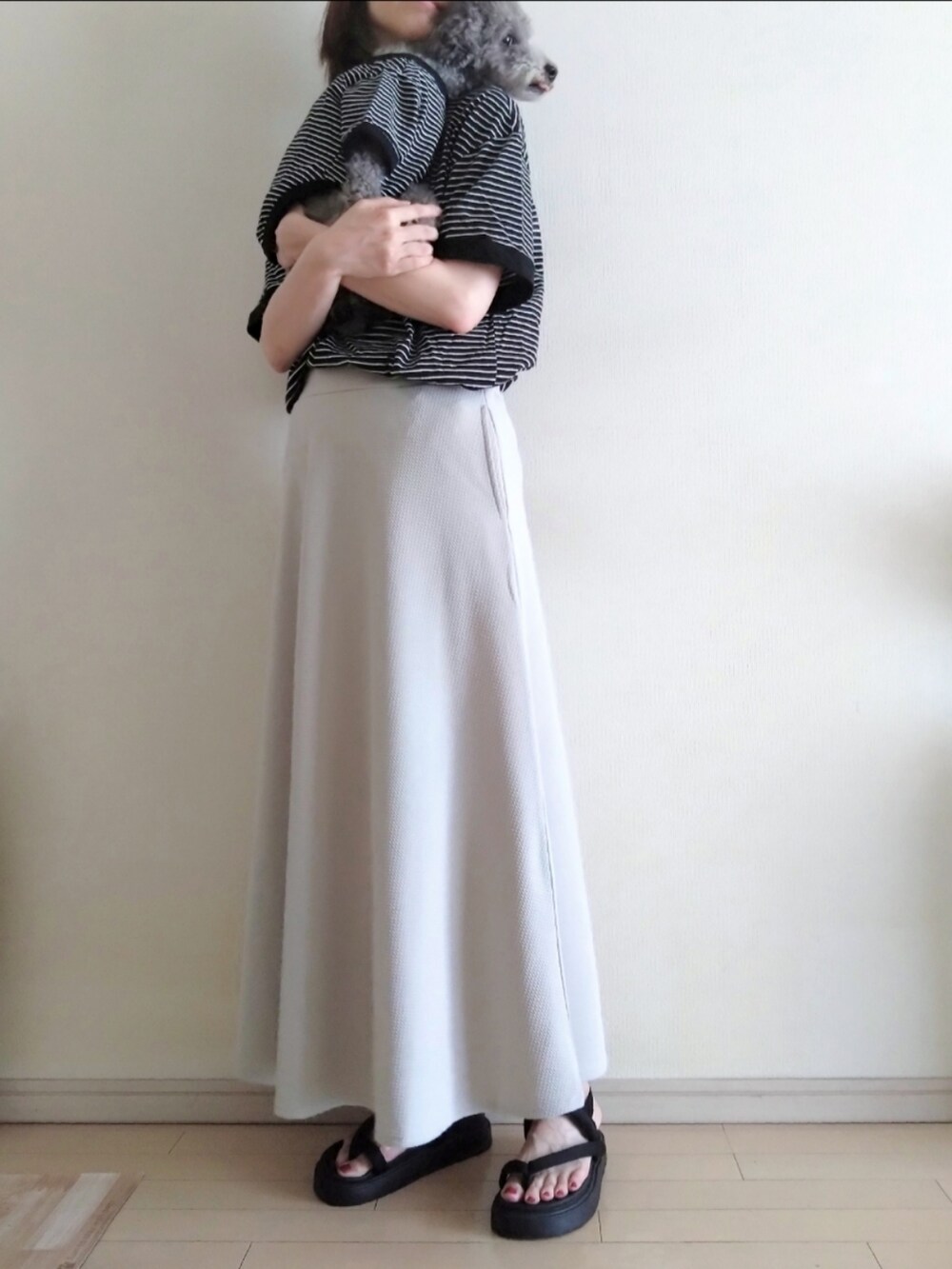 グレー系のスカート、ブラック系のTシャツ/カットソー、ブラック系のサンダルを着用したレディースの夏コーディネートの2枚目の写真