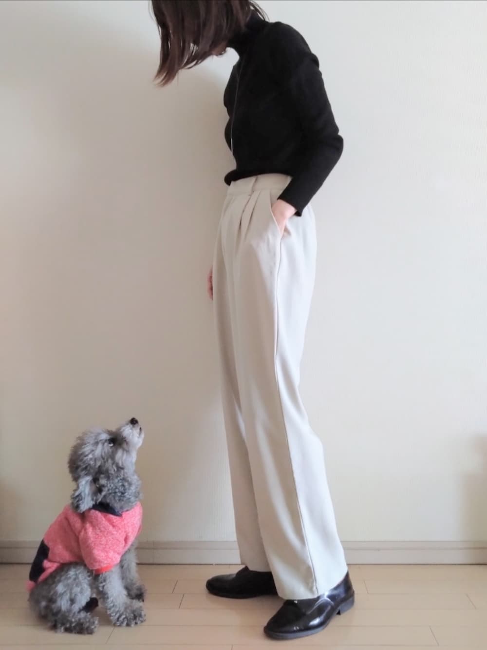 ブラック系のチェスターコート、ブラック系のニット/セーター、ホワイト系のその他パンツを着用したレディースの冬コーディネートの2枚目の写真