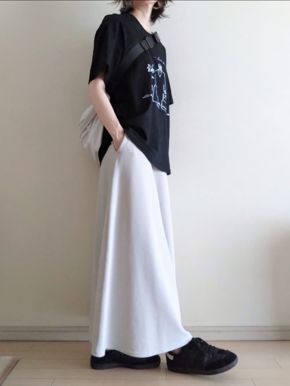 ブラック系のTシャツ/カットソー、グレー系のスカート、ホワイト系のボディバッグ/ウエストポーチを着用したレディースの夏コーディネートの2枚目の写真