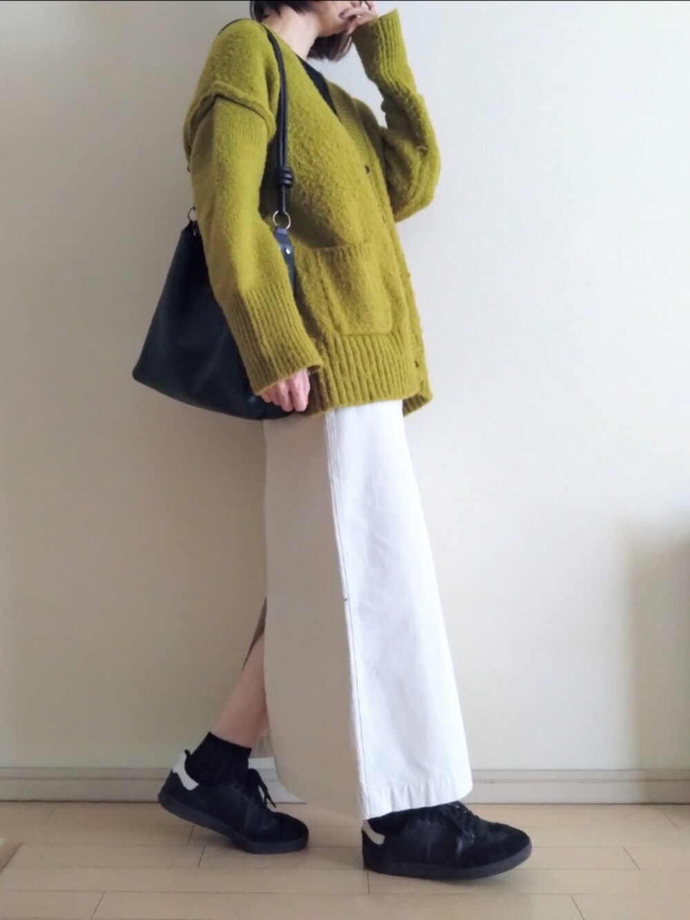 グリーン系のカーディガン/ボレロ、ブラック系のTシャツ/カットソー、ホワイト系のスカートを着用したレディースの秋コーディネートの2枚目の写真