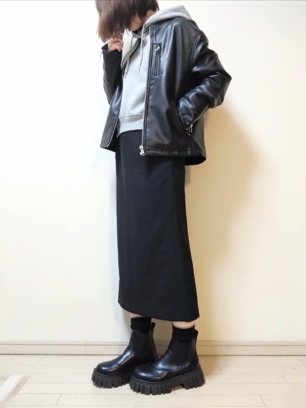 ブラック系のライダースジャケット、グレー系のパーカー、ブラック系のスカートを着用したレディースの春コーディネートの2枚目の写真