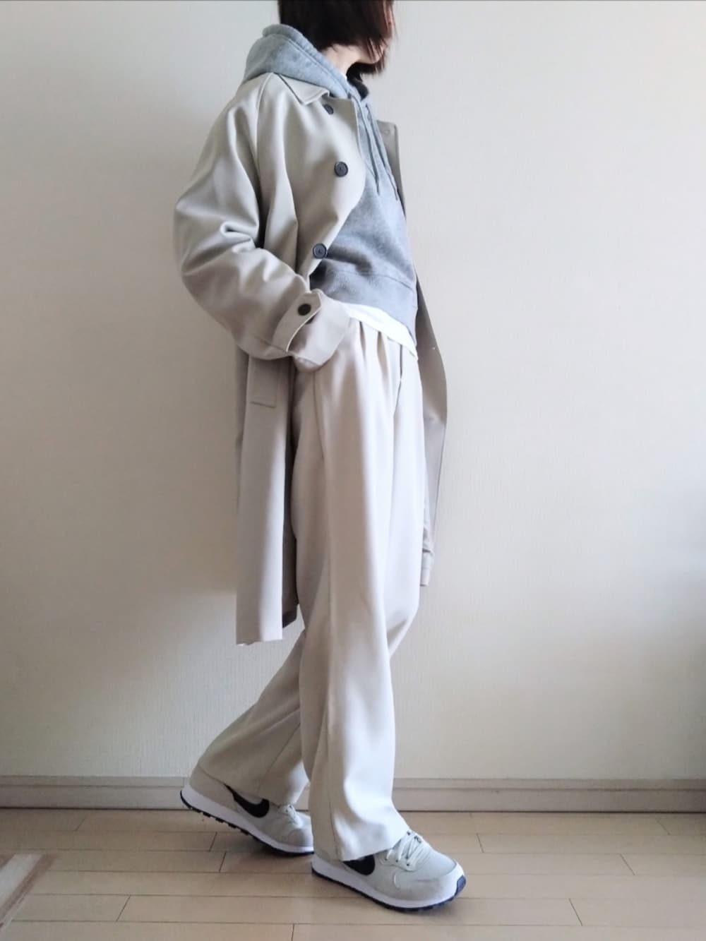 ベージュ系のステンカラーコート、グレー系のパーカー、ホワイト系のTシャツ/カットソーを着用したレディースの冬コーディネートの2枚目の写真
