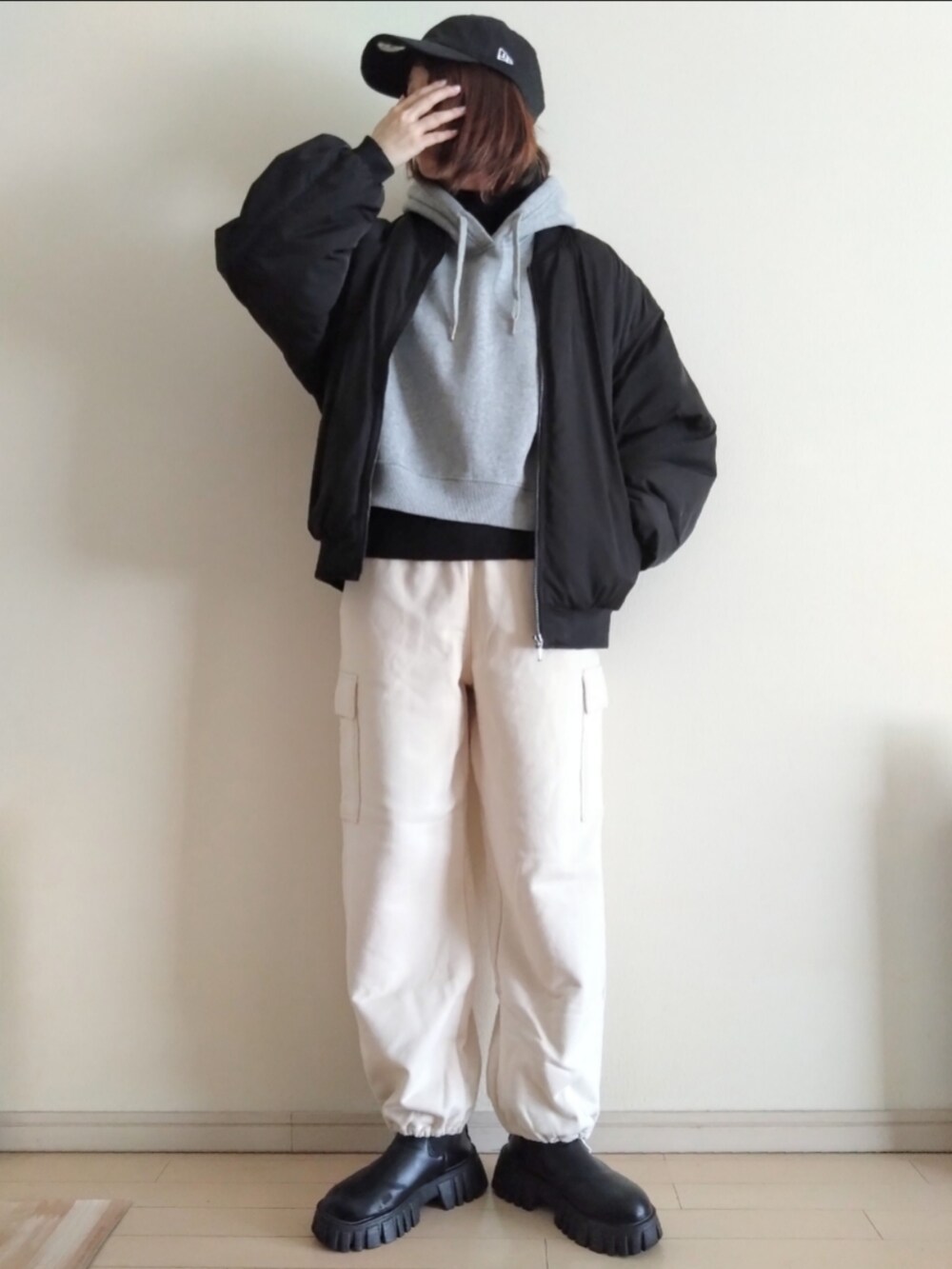 グレー系のパーカー、ブラック系のブルゾン、ホワイト系のカーゴパンツを着用したレディースの冬コーディネートの3枚目の写真