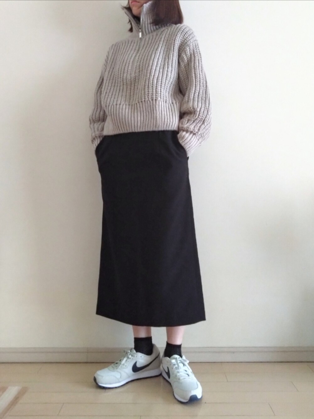 ベージュ系のニット/セーター、グレー系のTシャツ/カットソー、ブラック系のスカートを着用したレディースの春コーディネートの3枚目の写真