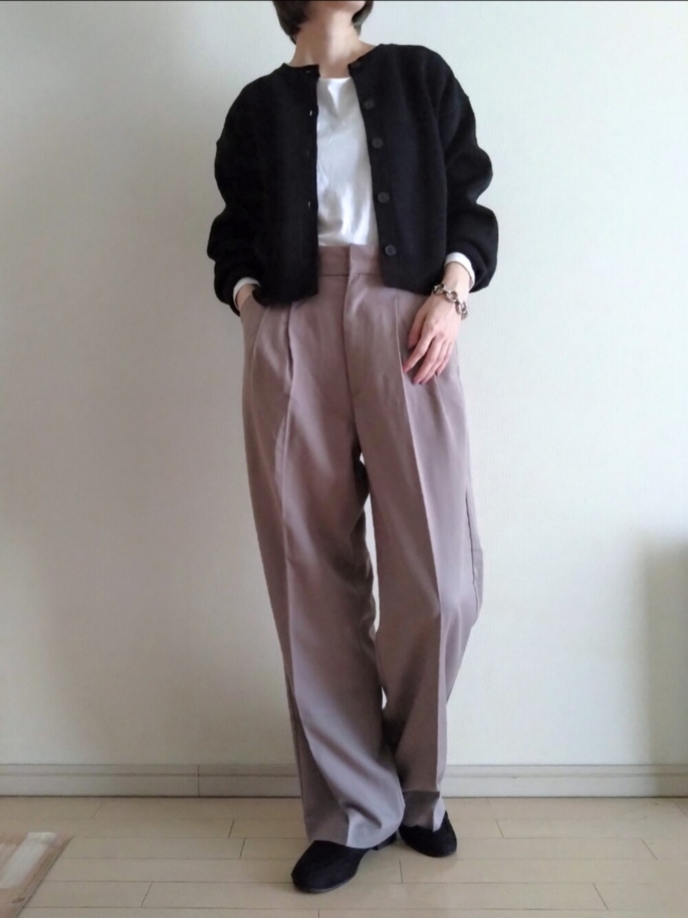 ブラック系のカーディガン/ボレロ、ホワイト系のTシャツ/カットソー、ベージュ系のスラックスを着用したレディースの春コーディネートの2枚目の写真