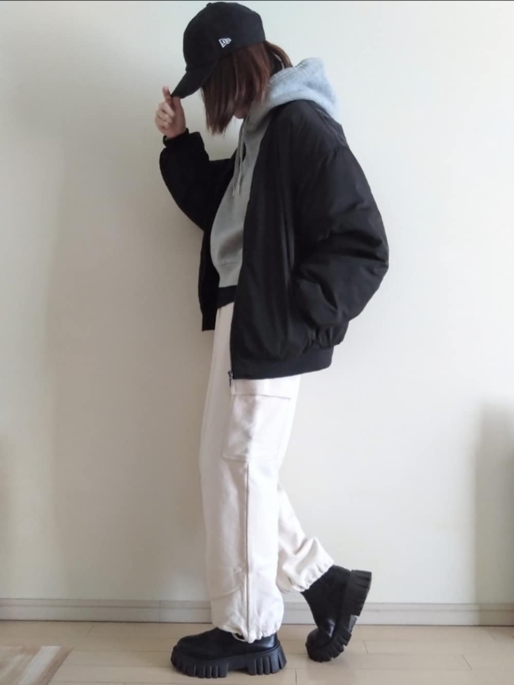 グレー系のパーカー、ブラック系のブルゾン、ホワイト系のカーゴパンツを着用したレディースの冬コーディネートの2枚目の写真